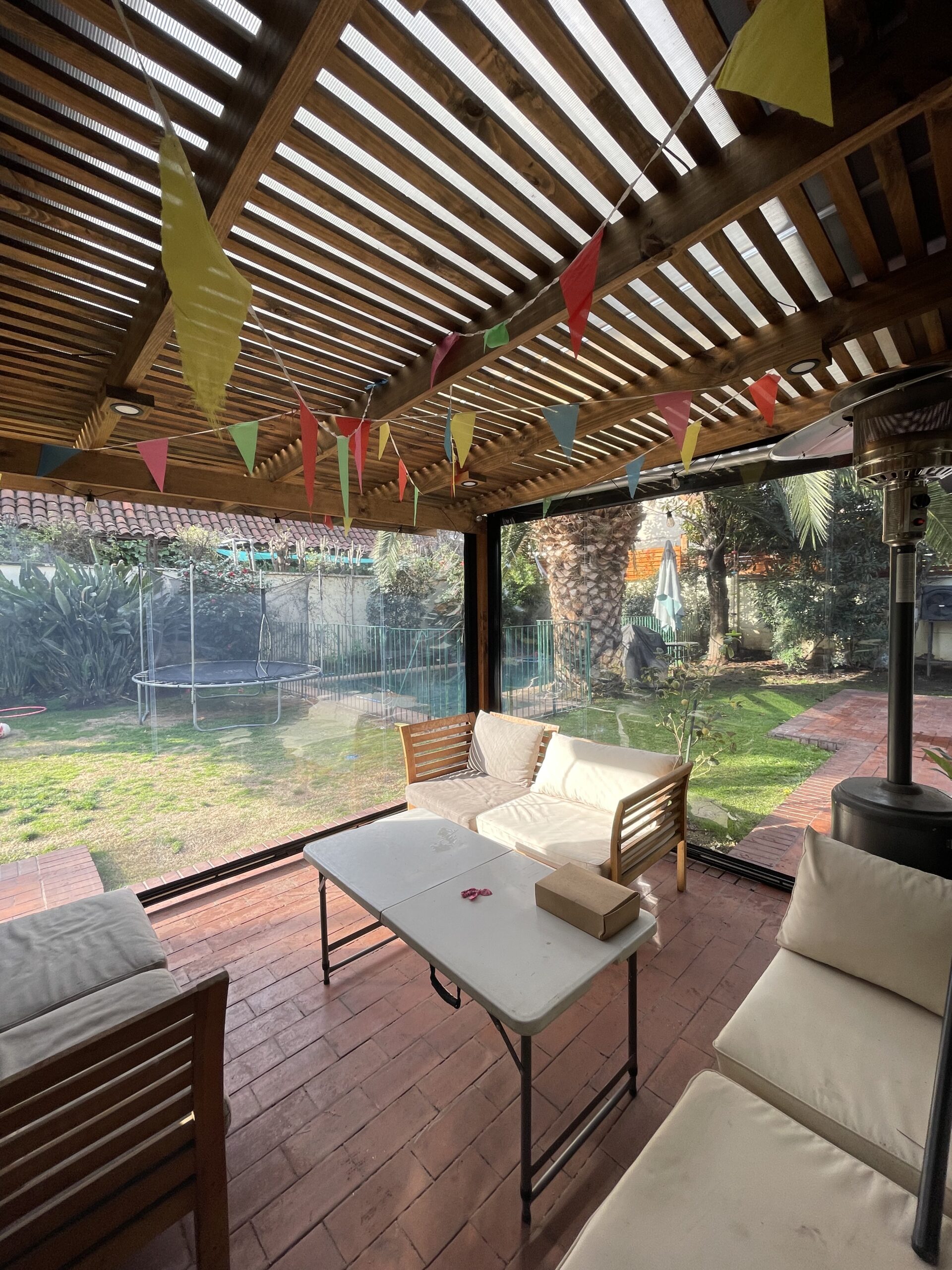 Terraza de departamento moderna con cierre de cristal plegable, amoblada con sofá. Terraza protegida del clima.