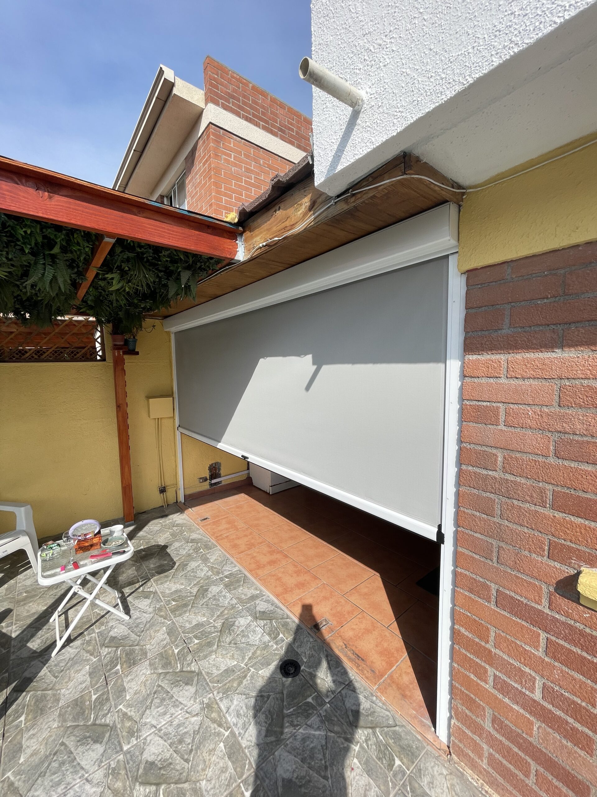 Terraza de departamento moderna con cierre de cristal plegable, amoblada con sofá. Terraza protegida del clima.