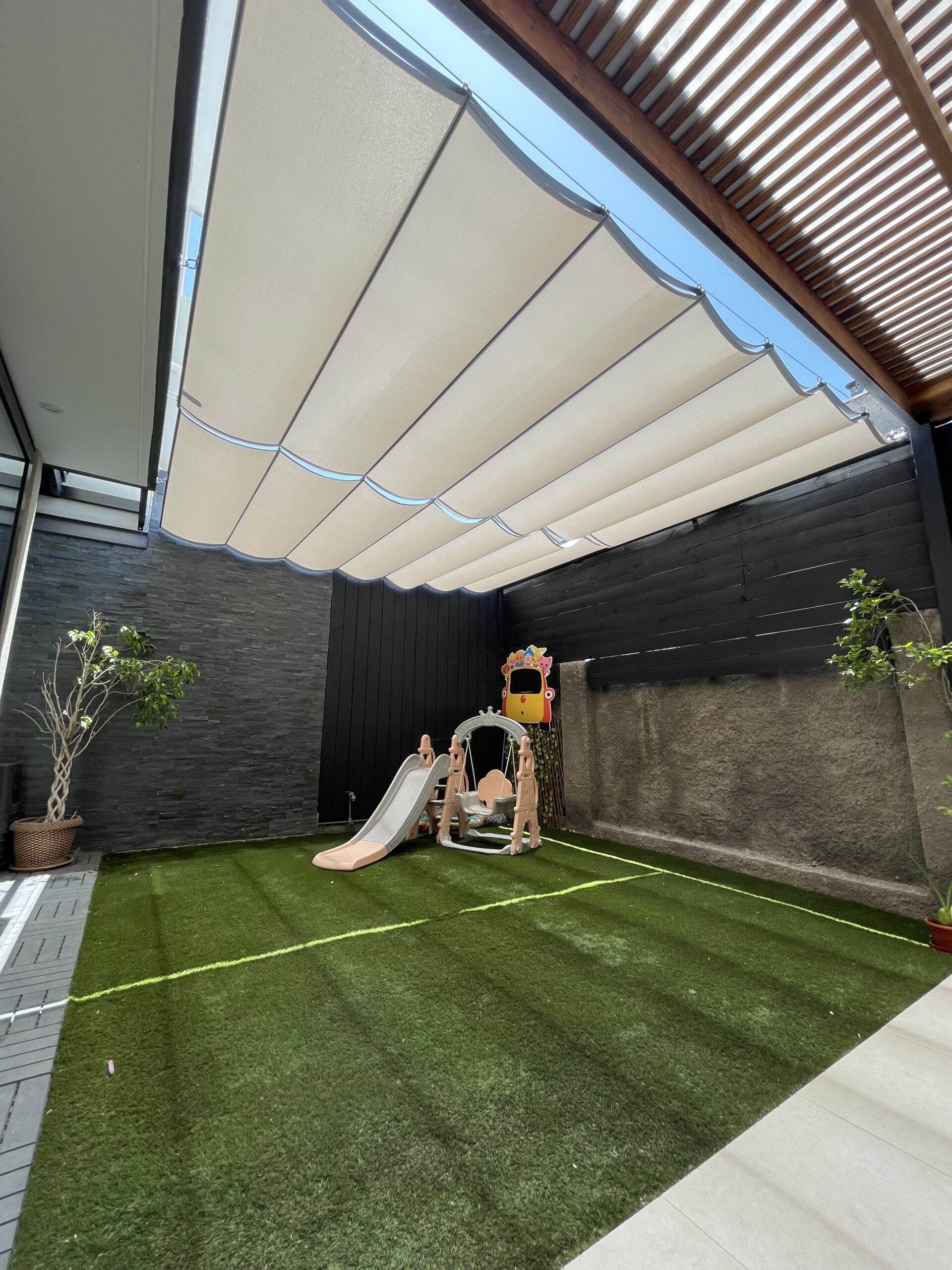 Cierre vertical tradicional de PVC transparente instalado en terraza moderna, con estructura negra y lona semi flexible, ideal para protección contra viento, lluvia y frío sin perder visibilidad exterior.