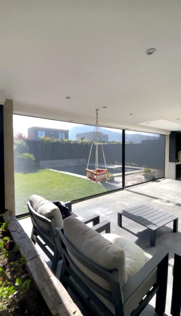 Terraza de departamento moderna con cierre de cristal plegable, amoblada con sofá. Terraza protegida del clima.