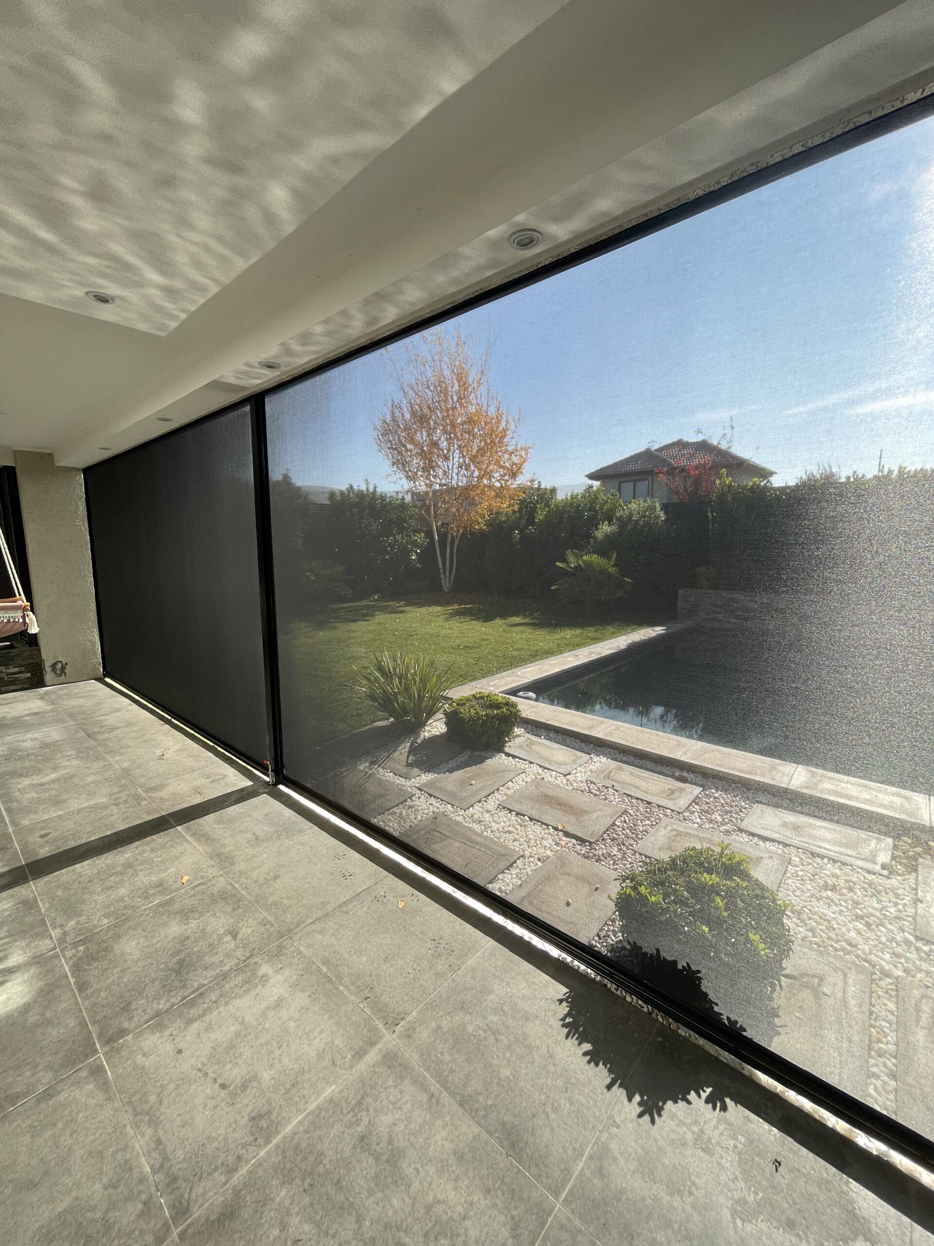 Terraza de departamento moderna con cierre de cristal plegable, amoblada con sofá. Terraza protegida del clima.