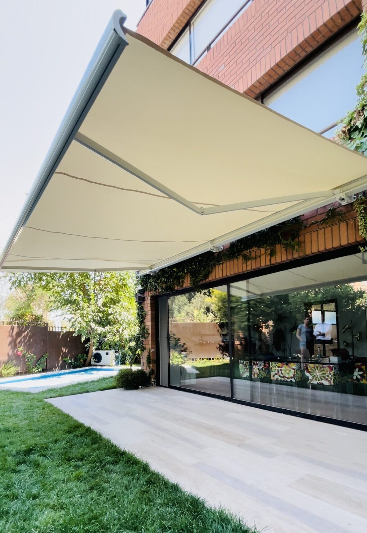 Terraza de departamento moderna con cierre de cristal plegable, amoblada con sofá. Terraza protegida del clima.