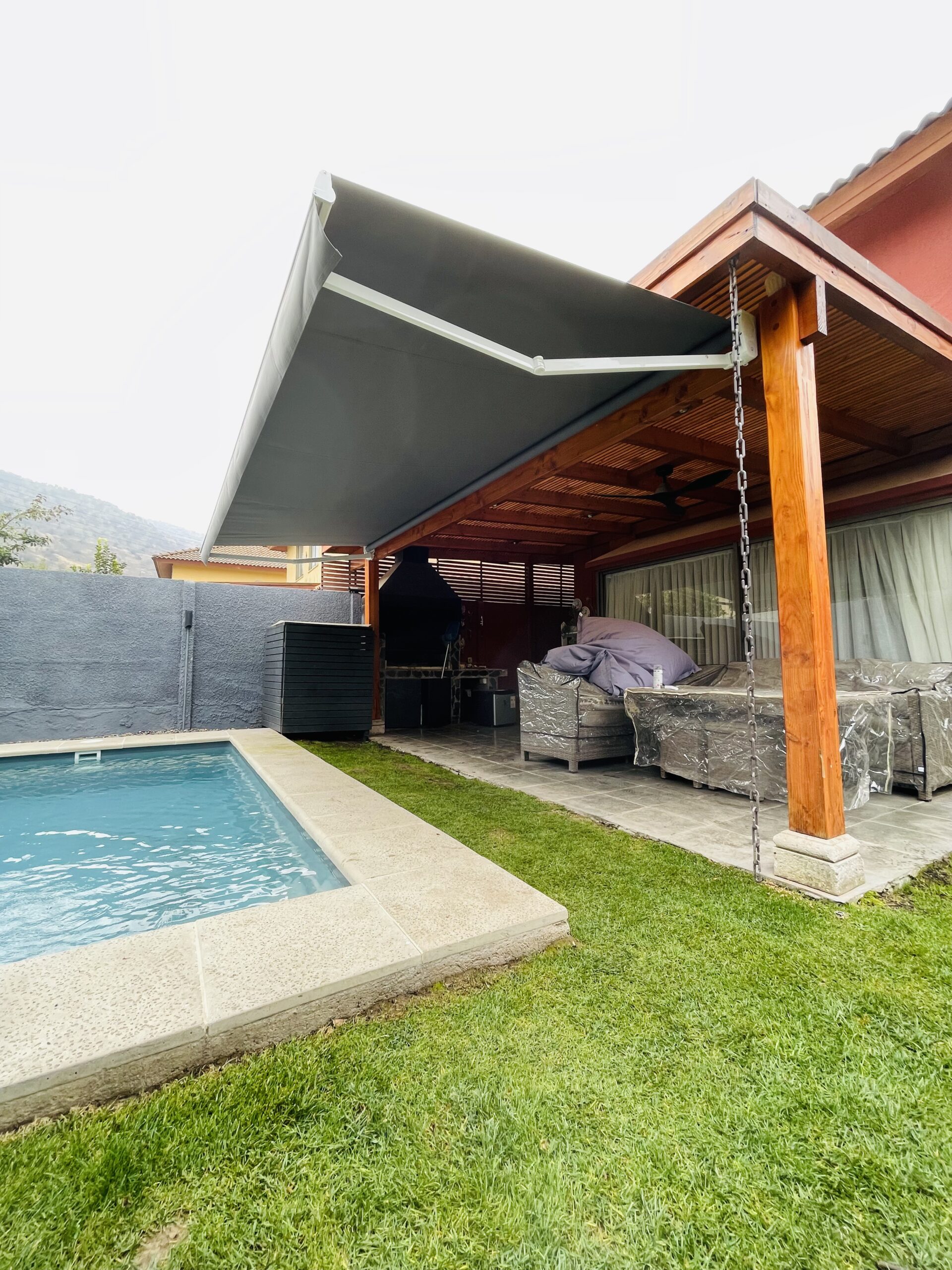 Terraza de departamento moderna con cierre de cristal plegable, amoblada con sofá. Terraza protegida del clima.