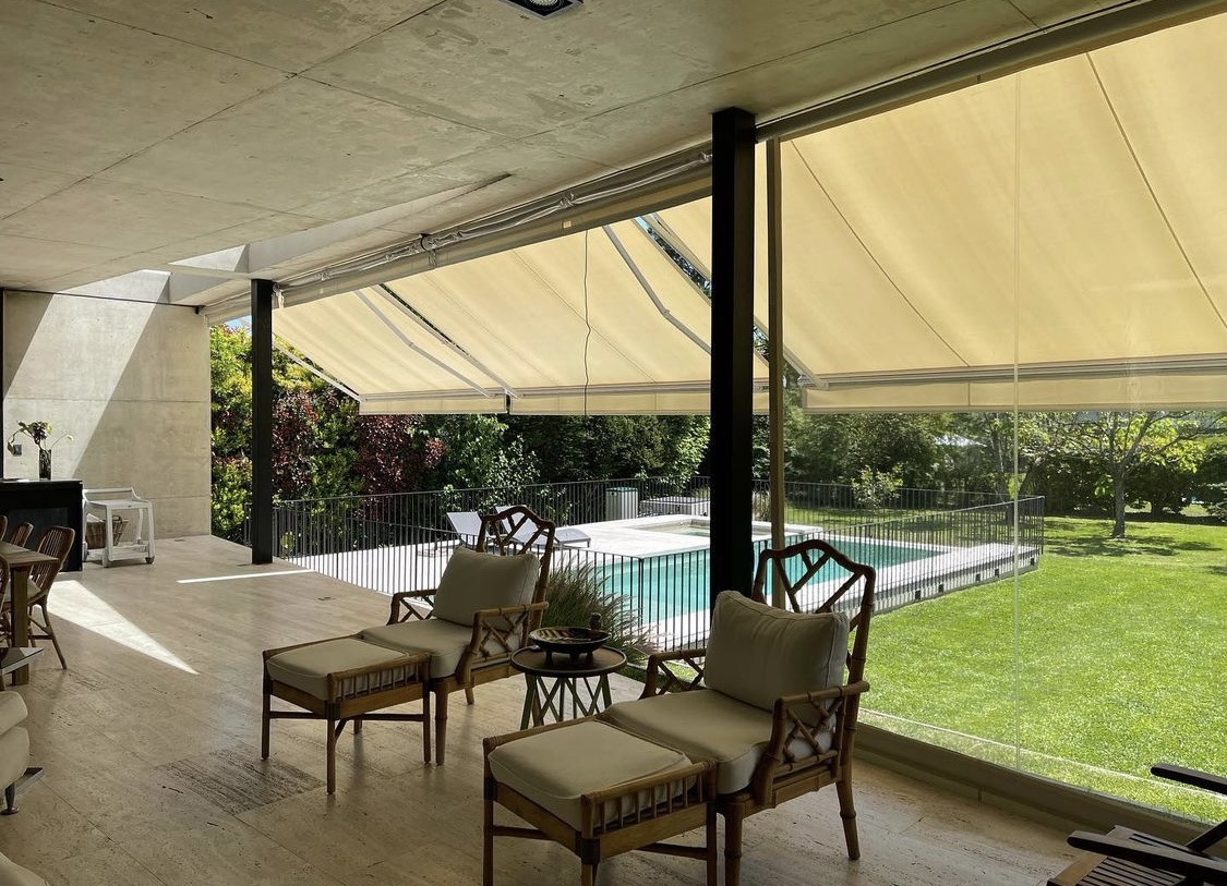 Terraza de departamento moderna con cierre de cristal plegable, amoblada con sofá. Terraza protegida del clima.