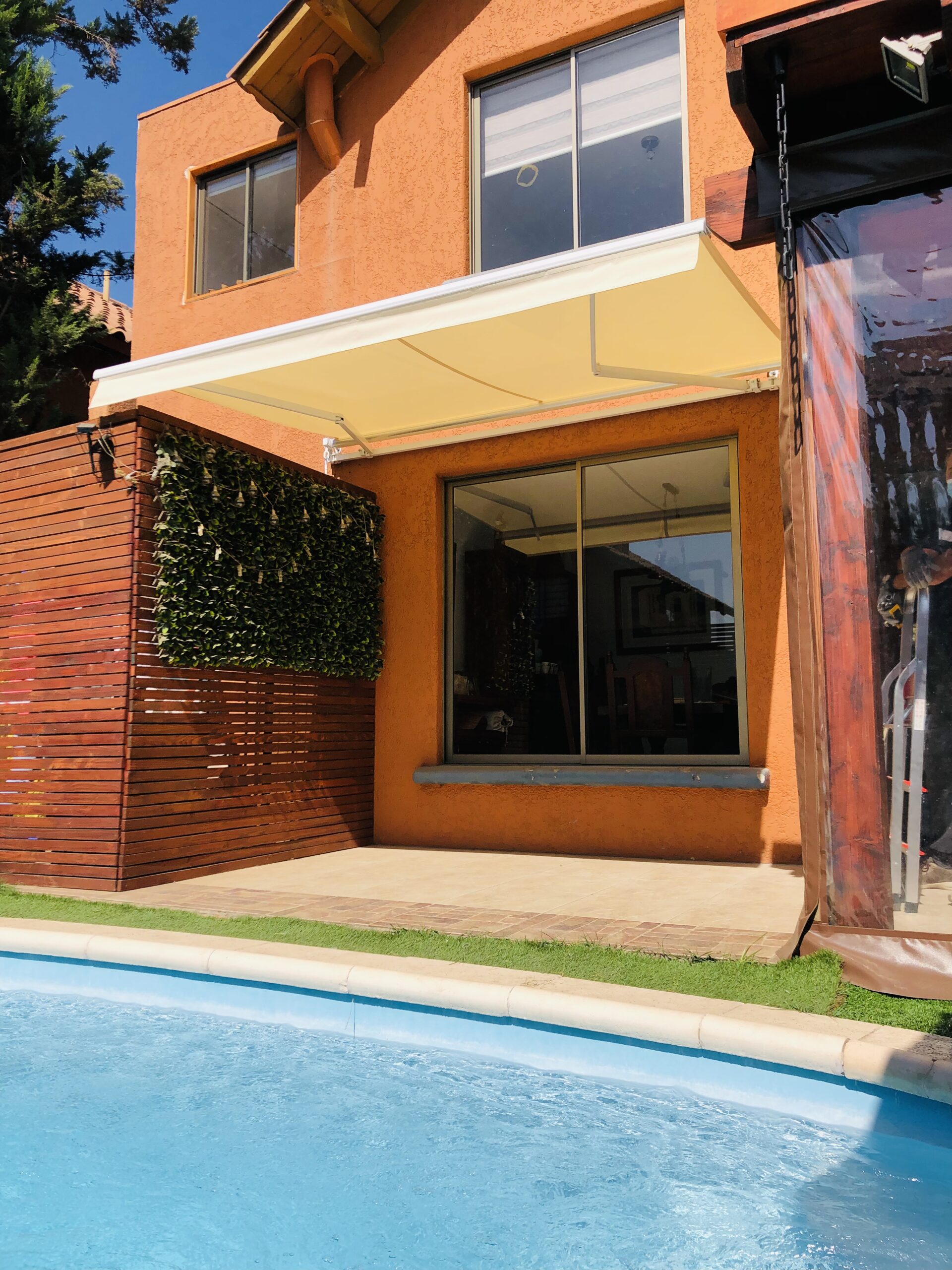 Terraza de departamento moderna con cierre de cristal plegable, amoblada con sofá. Terraza protegida del clima.