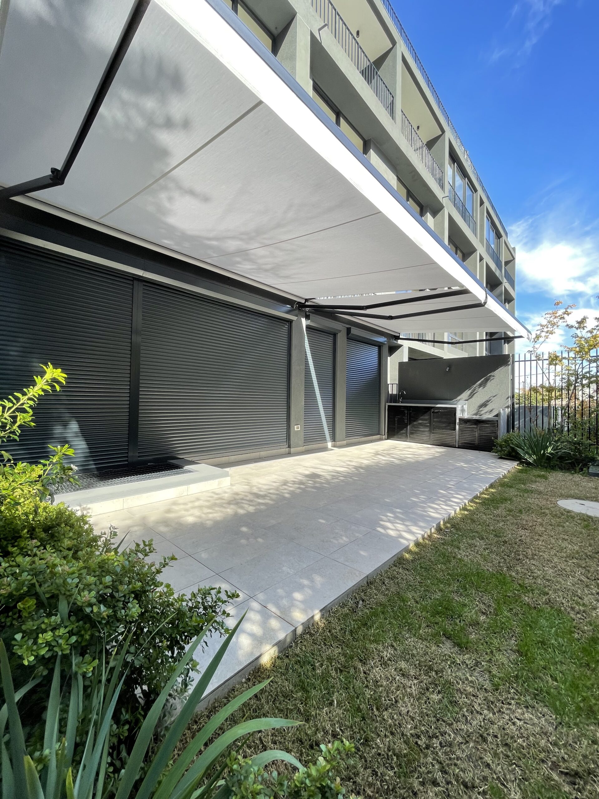 Terraza de departamento moderna con cierre de cristal plegable, amoblada con sofá. Terraza protegida del clima.