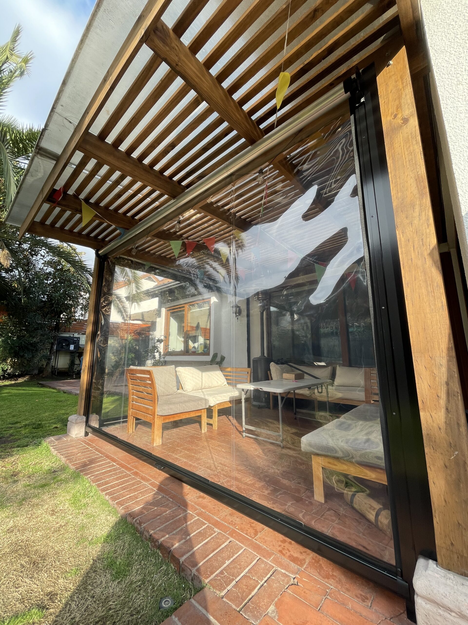 Terraza de departamento moderna con cierre de cristal plegable, amoblada con sofá. Terraza protegida del clima.