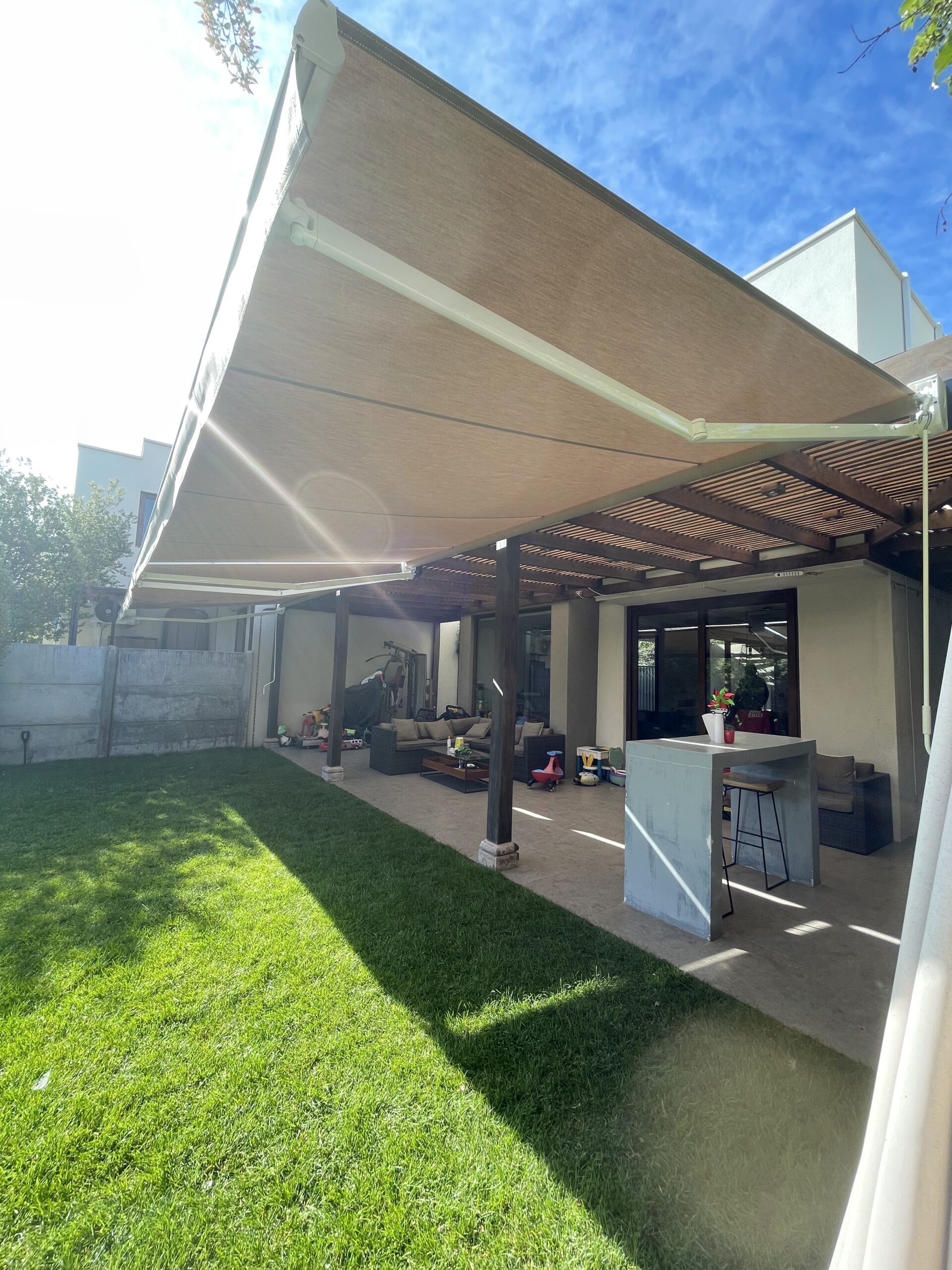 Terraza de departamento moderna con cierre de cristal plegable, amoblada con sofá. Terraza protegida del clima.