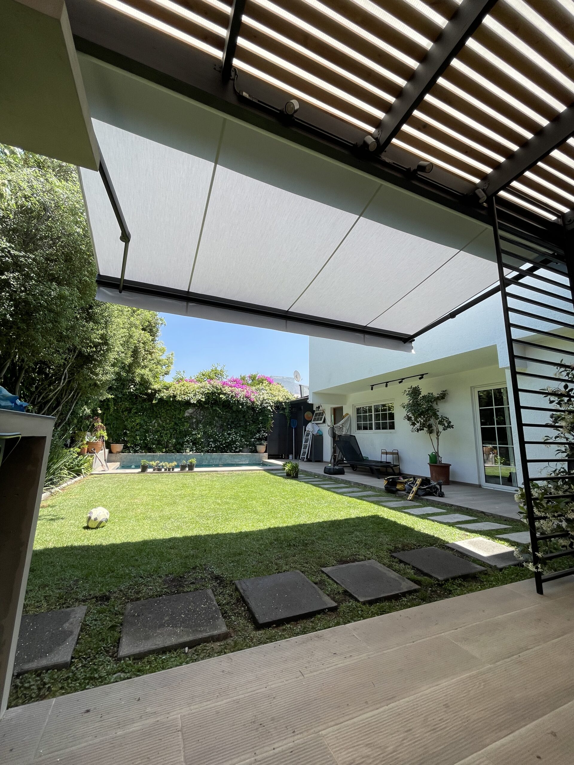 Terraza de departamento moderna con cierre de cristal plegable, amoblada con sofá. Terraza protegida del clima.