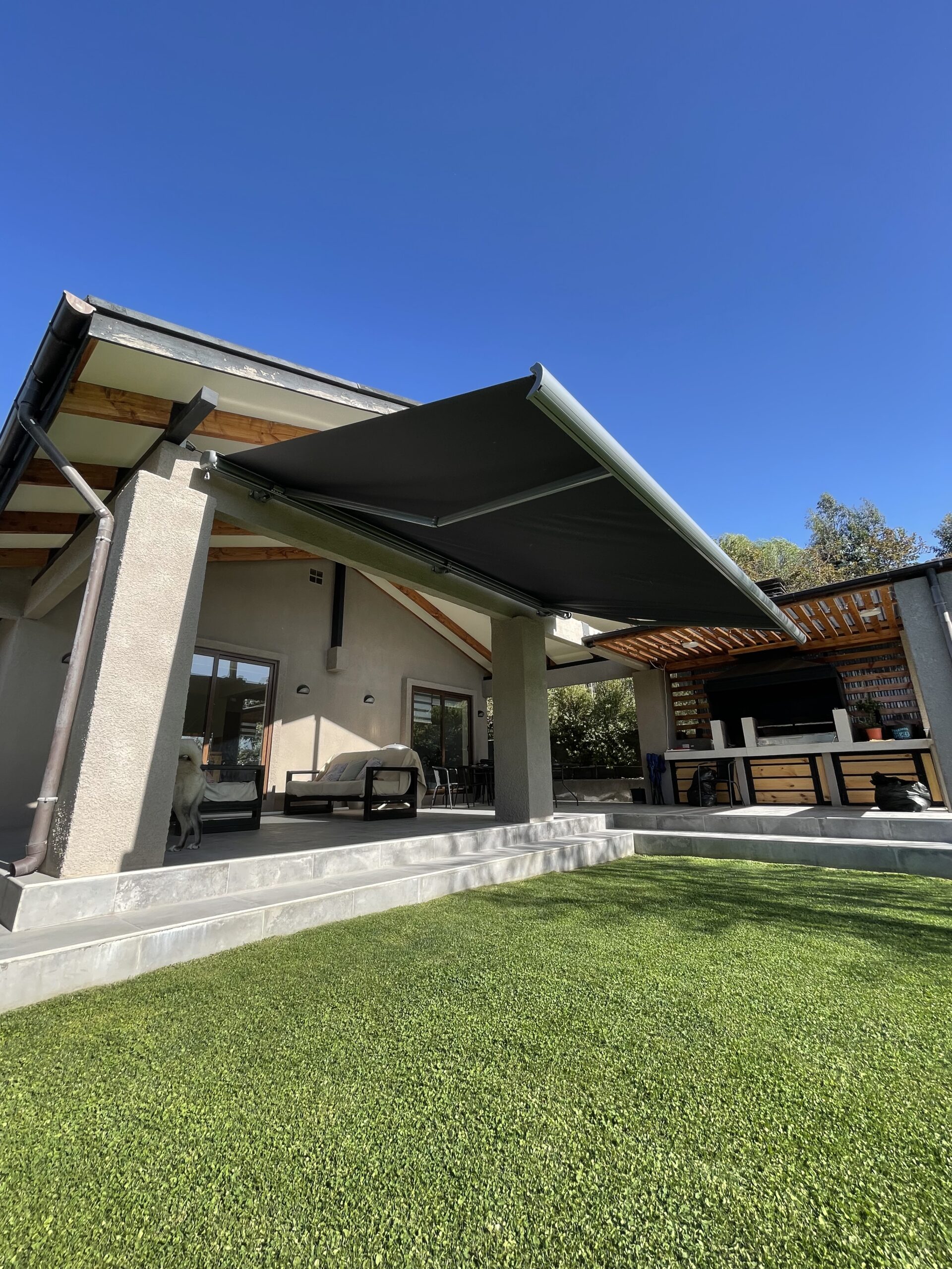 Terraza de departamento moderna con cierre de cristal plegable, amoblada con sofá. Terraza protegida del clima.