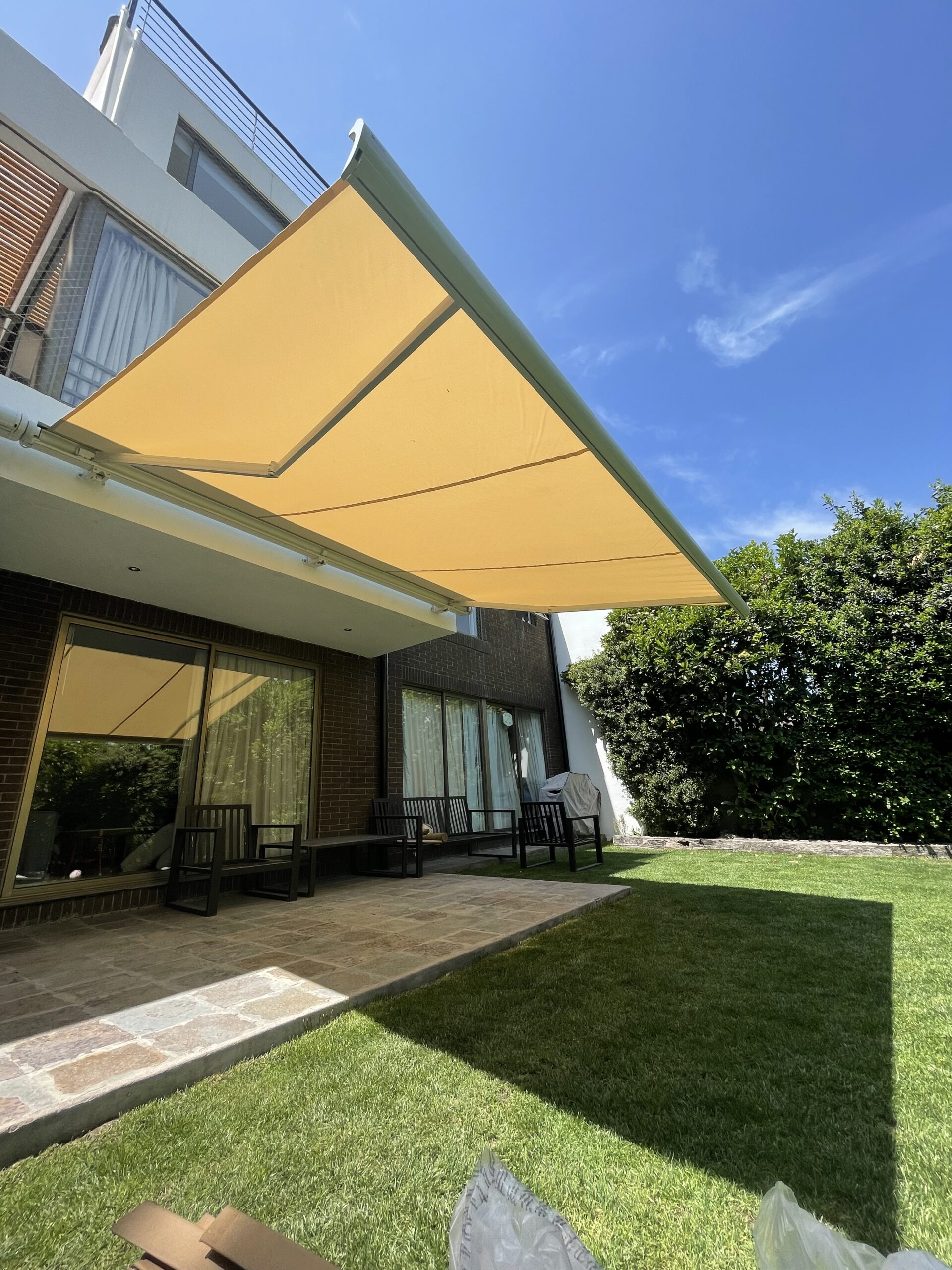 Terraza de departamento moderna con cierre de cristal plegable, amoblada con sofá. Terraza protegida del clima.