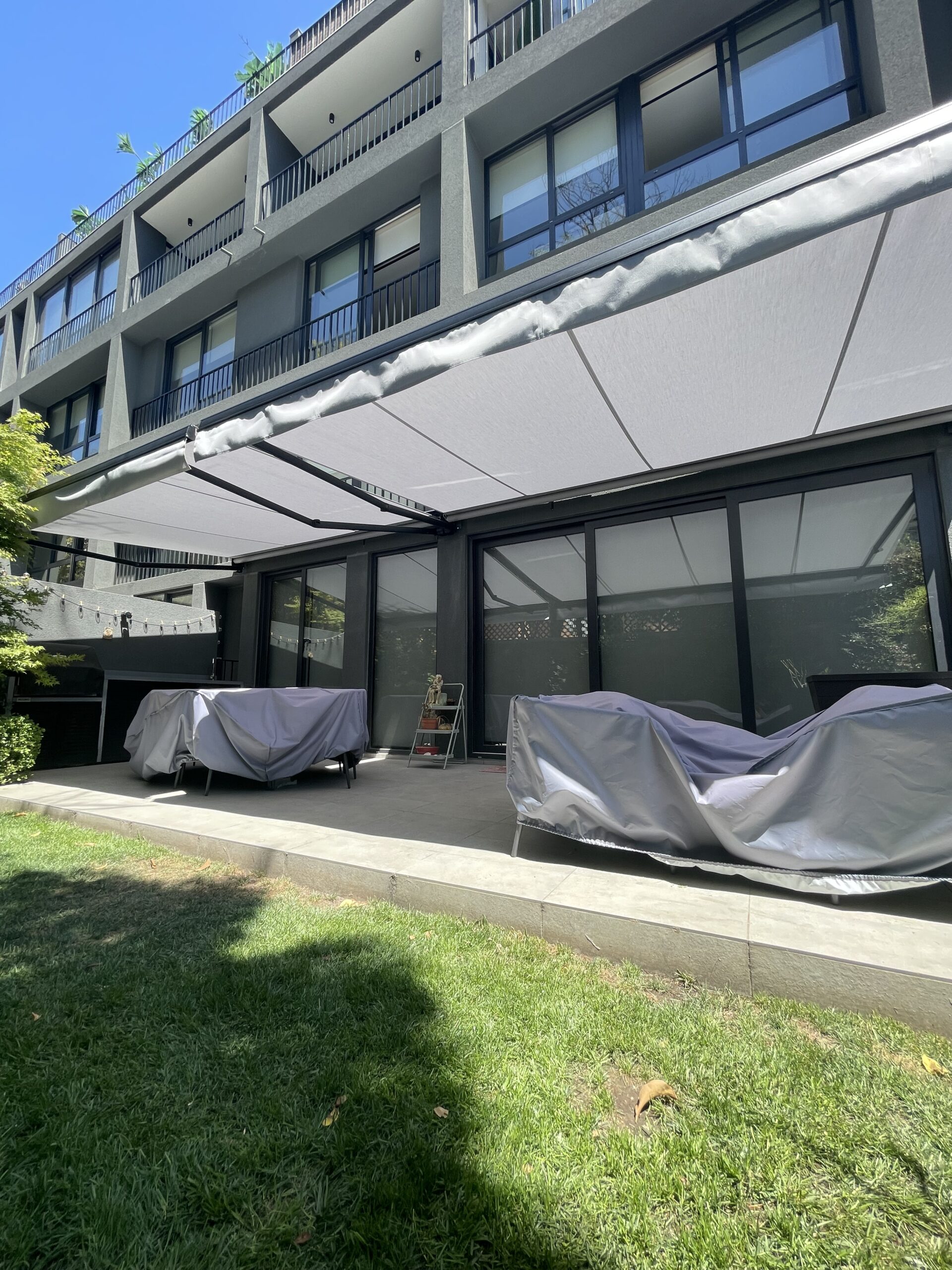 Terraza de departamento moderna con cierre de cristal plegable, amoblada con sofá. Terraza protegida del clima.