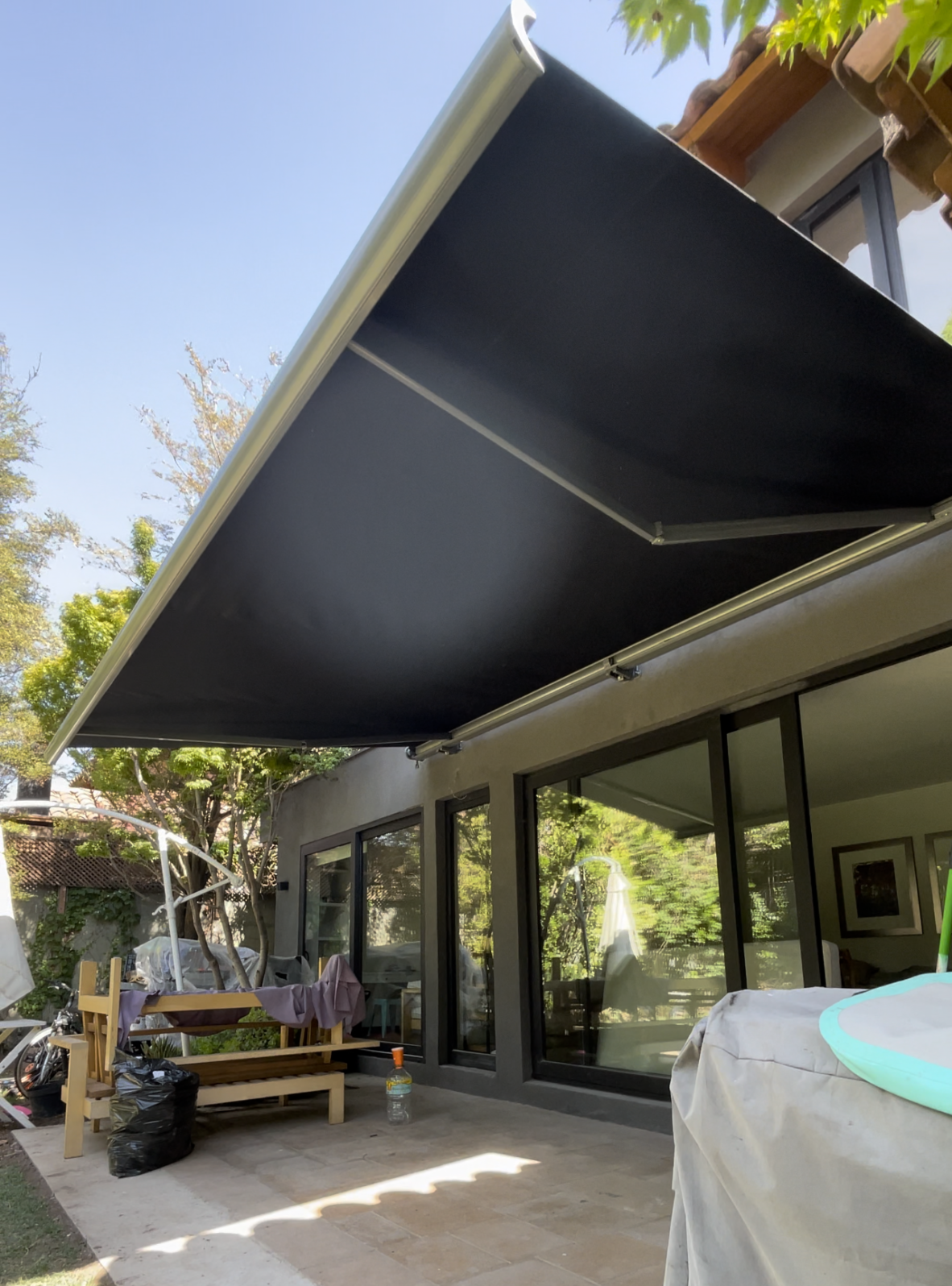 Terraza de departamento moderna con cierre de cristal plegable, amoblada con sofá. Terraza protegida del clima.