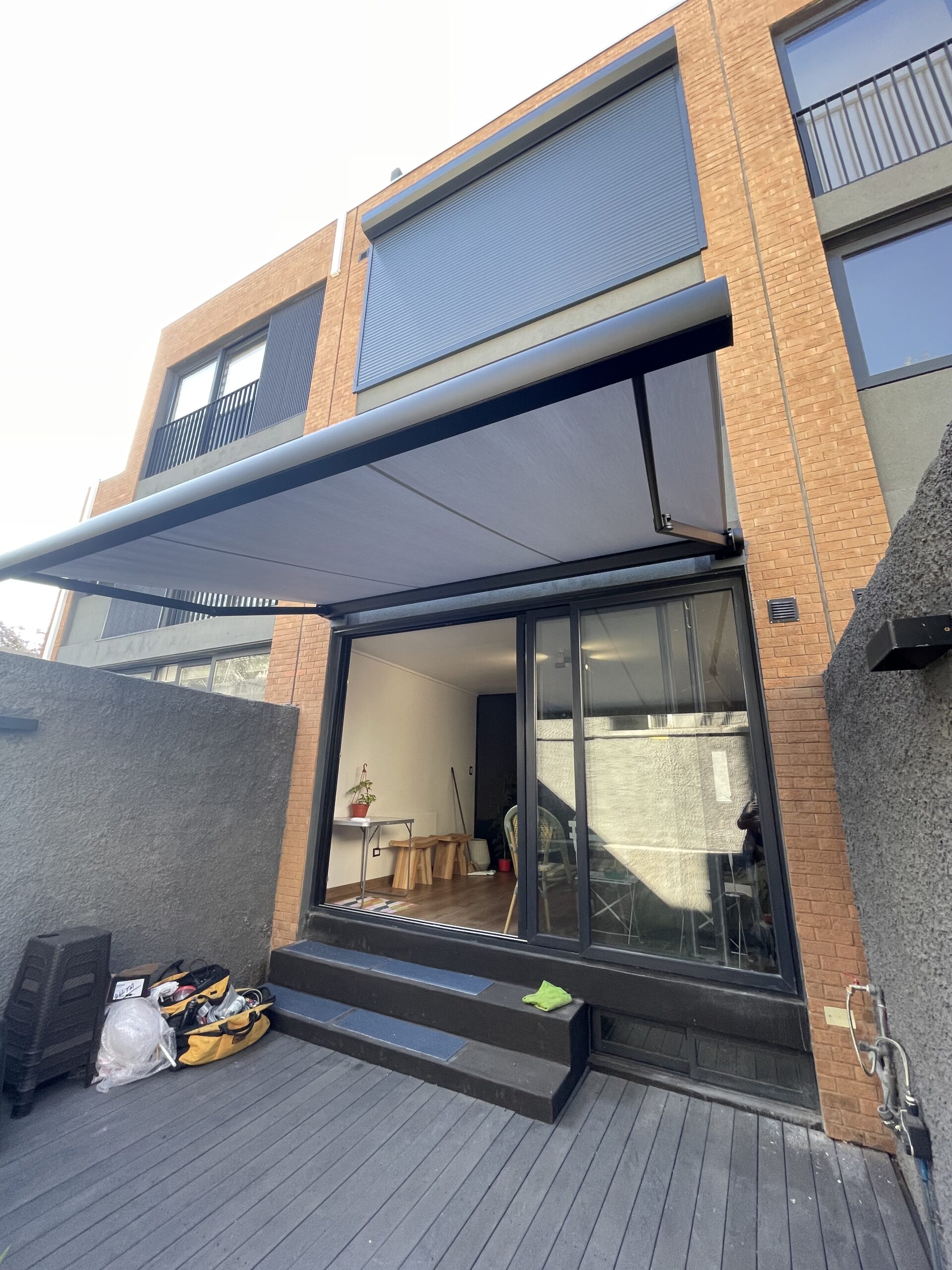 Terraza de departamento moderna con cierre de cristal plegable, amoblada con sofá. Terraza protegida del clima.