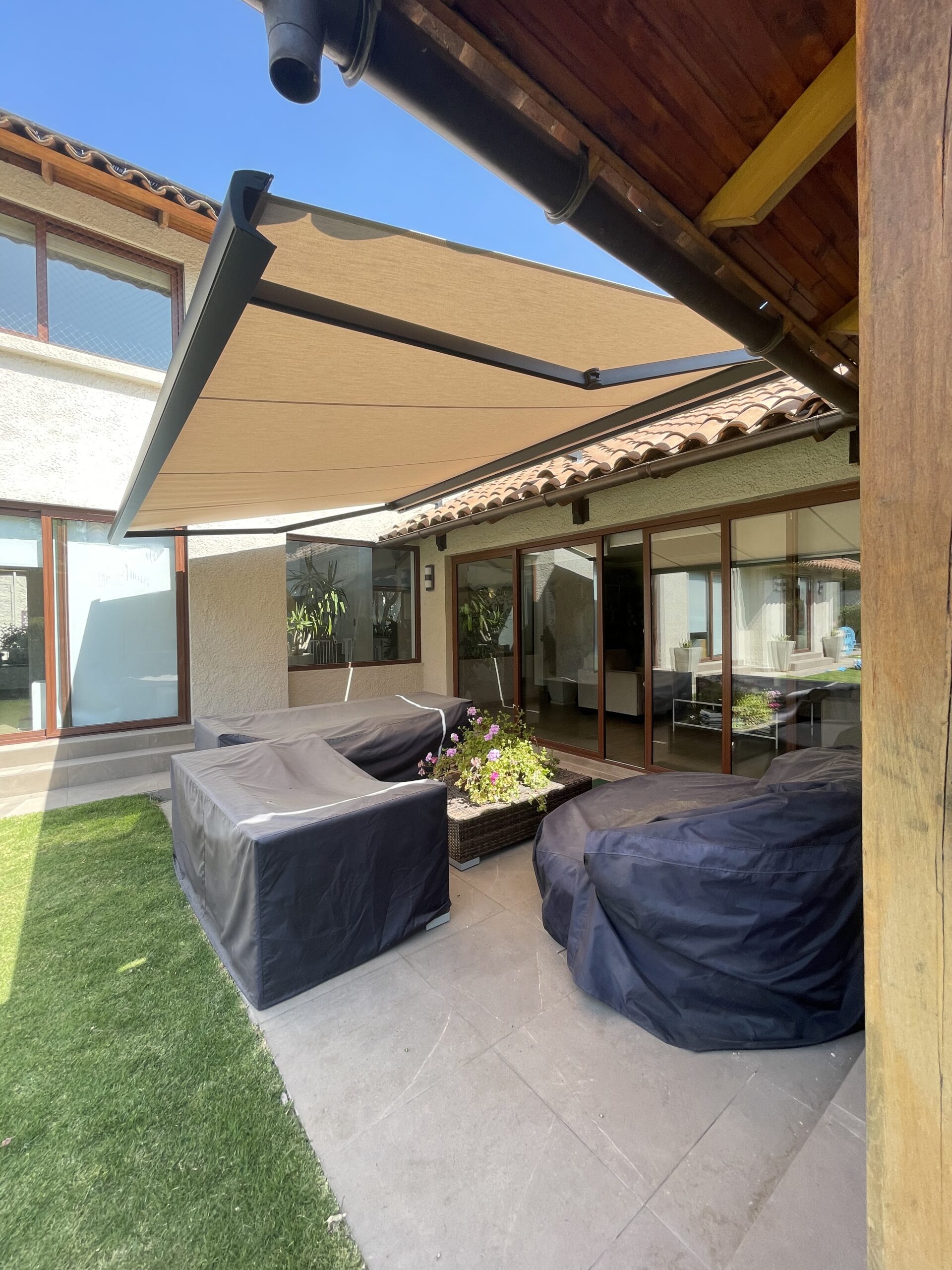 Terraza de departamento moderna con cierre de cristal plegable, amoblada con sofá. Terraza protegida del clima.