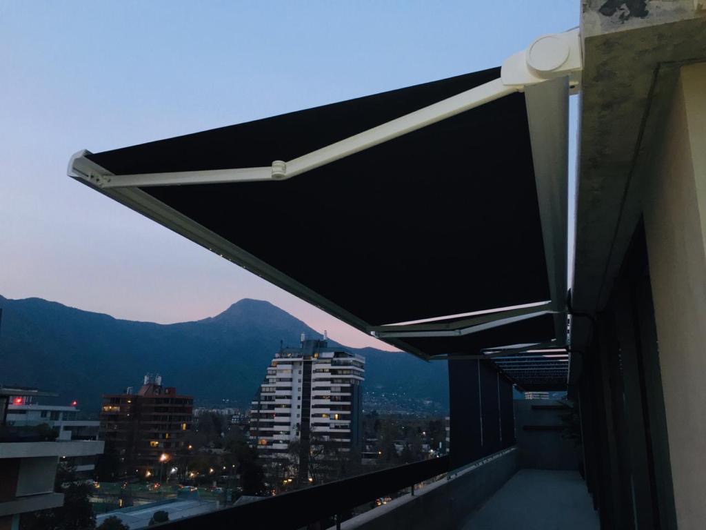 Terraza de departamento moderna con cierre de cristal plegable, amoblada con sofá. Terraza protegida del clima.