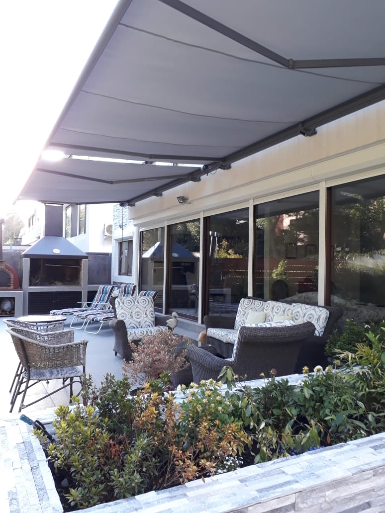 Terraza de departamento moderna con cierre de cristal plegable, amoblada con sofá. Terraza protegida del clima.