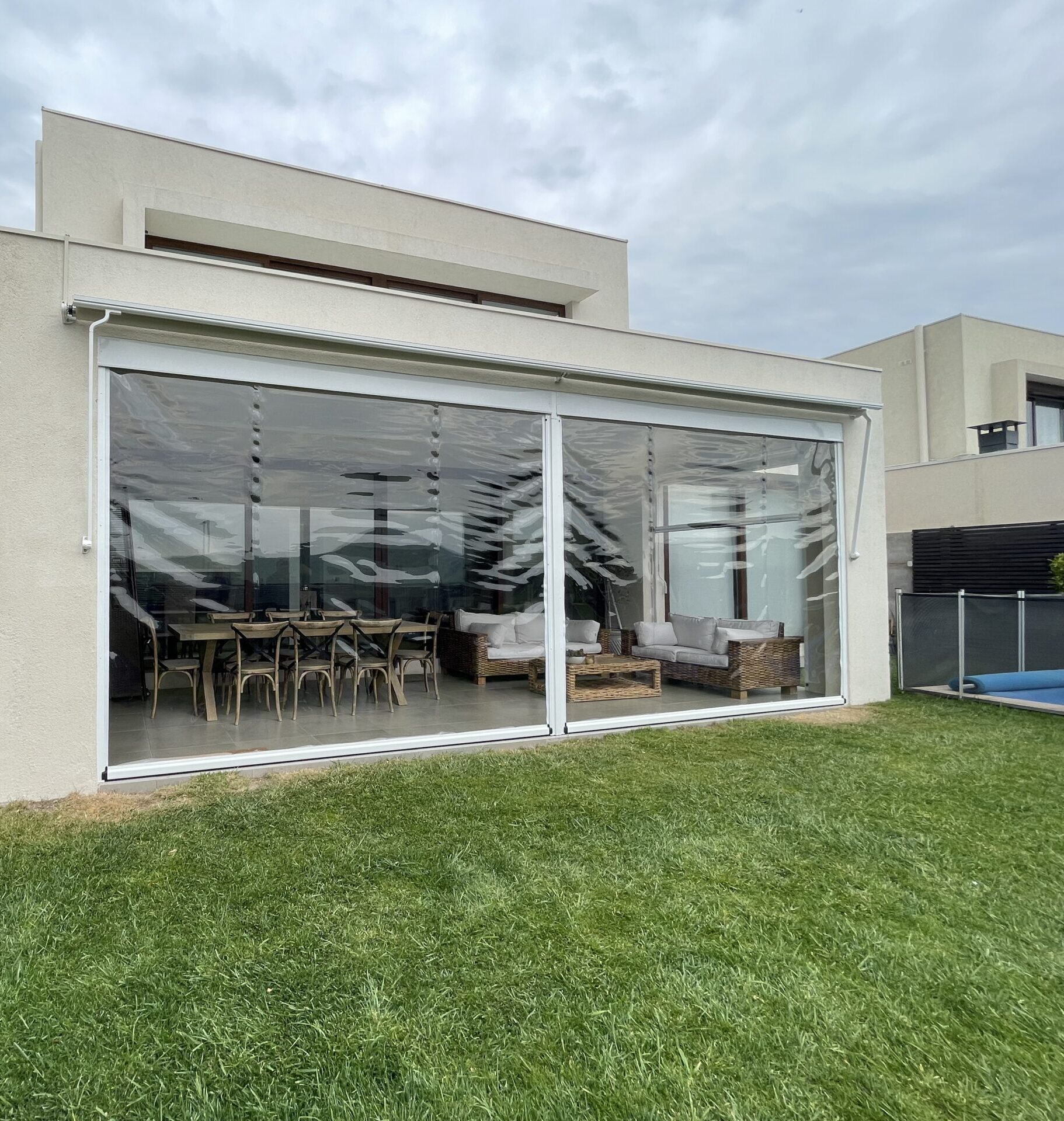 Terraza de departamento moderna con cierre de cristal plegable, amoblada con sofá. Terraza protegida del clima.