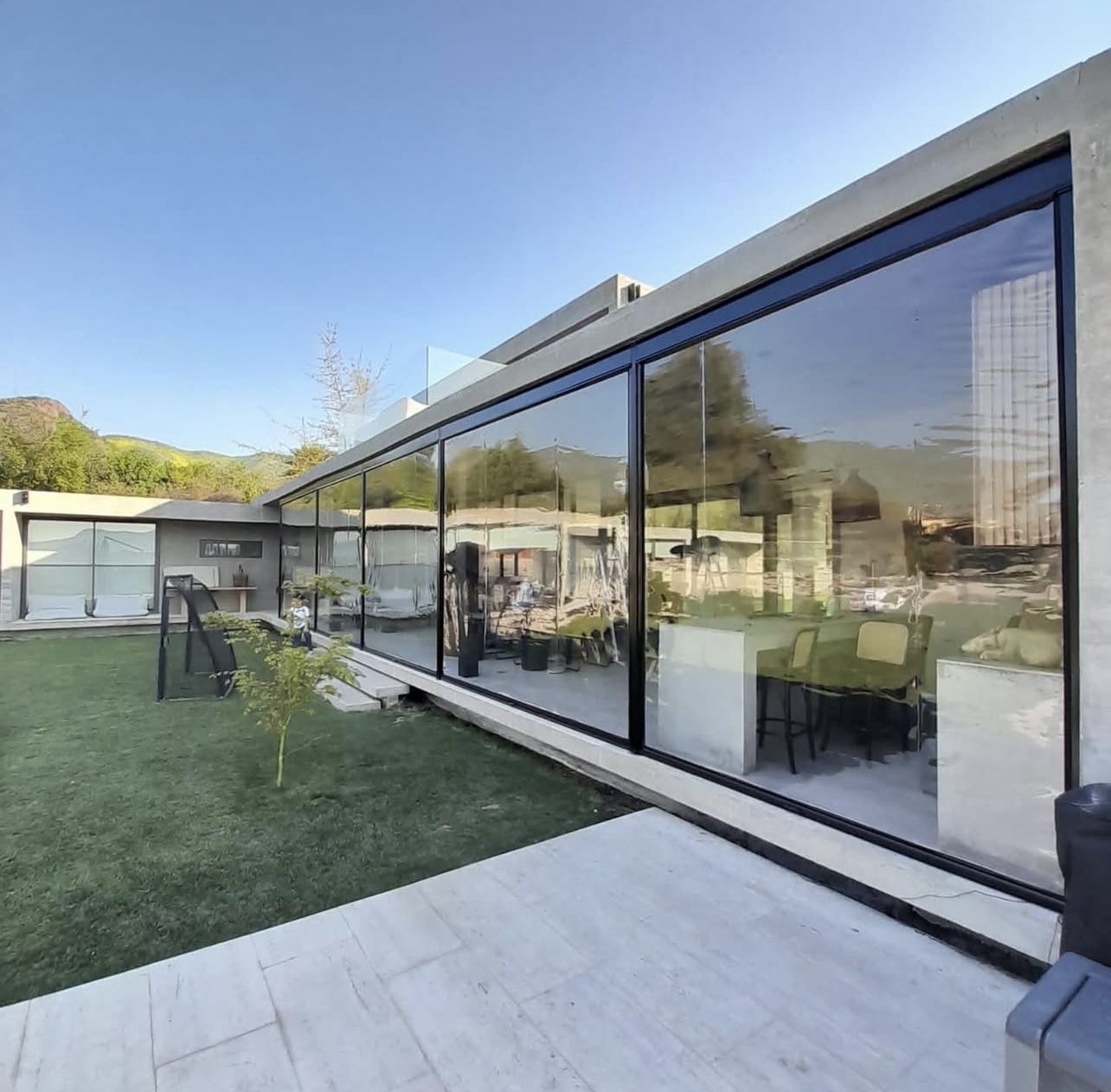 Terraza de departamento moderna con cierre de cristal plegable, amoblada con sofá. Terraza protegida del clima.