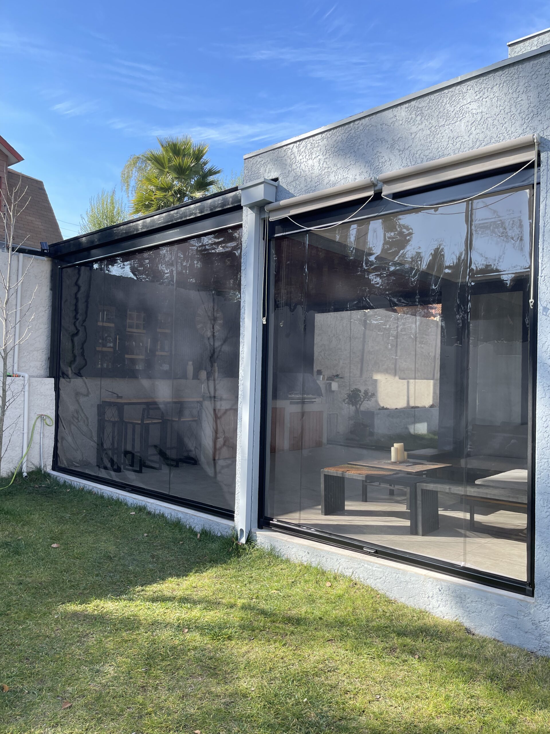 Terraza de departamento moderna con cierre de cristal plegable, amoblada con sofá. Terraza protegida del clima.