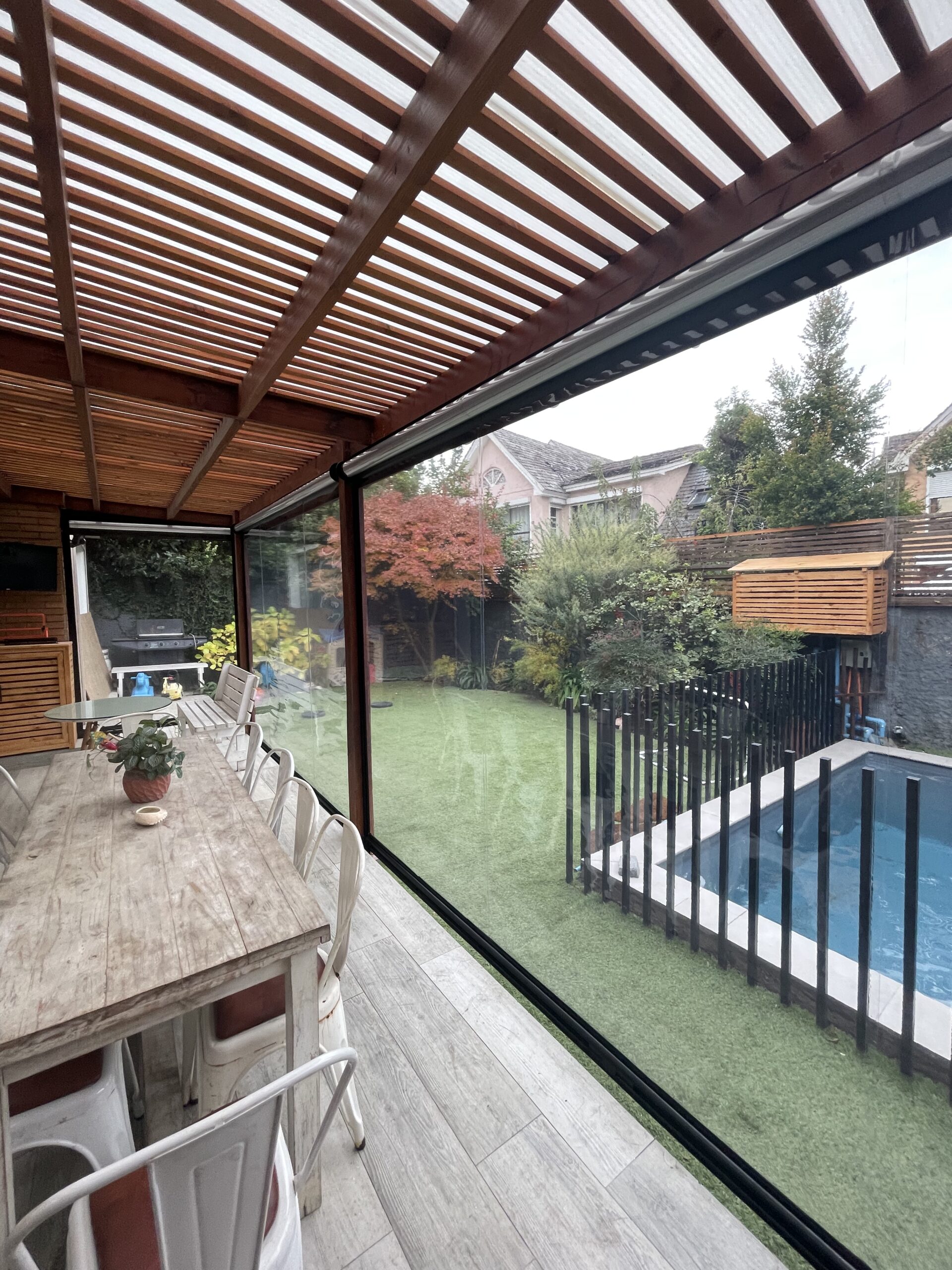 Terraza de departamento moderna con cierre de cristal plegable, amoblada con sofá. Terraza protegida del clima.