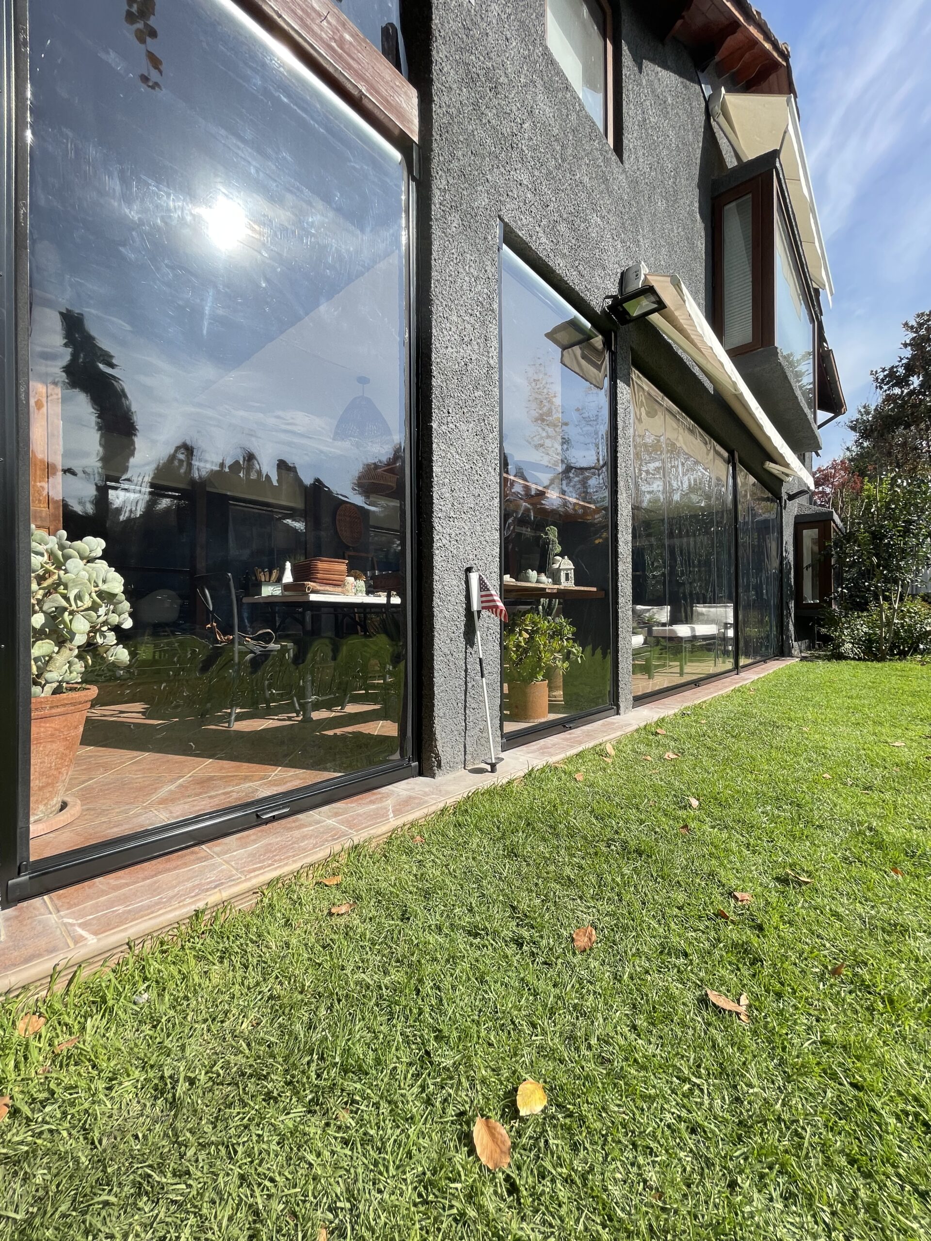Terraza de departamento moderna con cierre de cristal plegable, amoblada con sofá. Terraza protegida del clima.