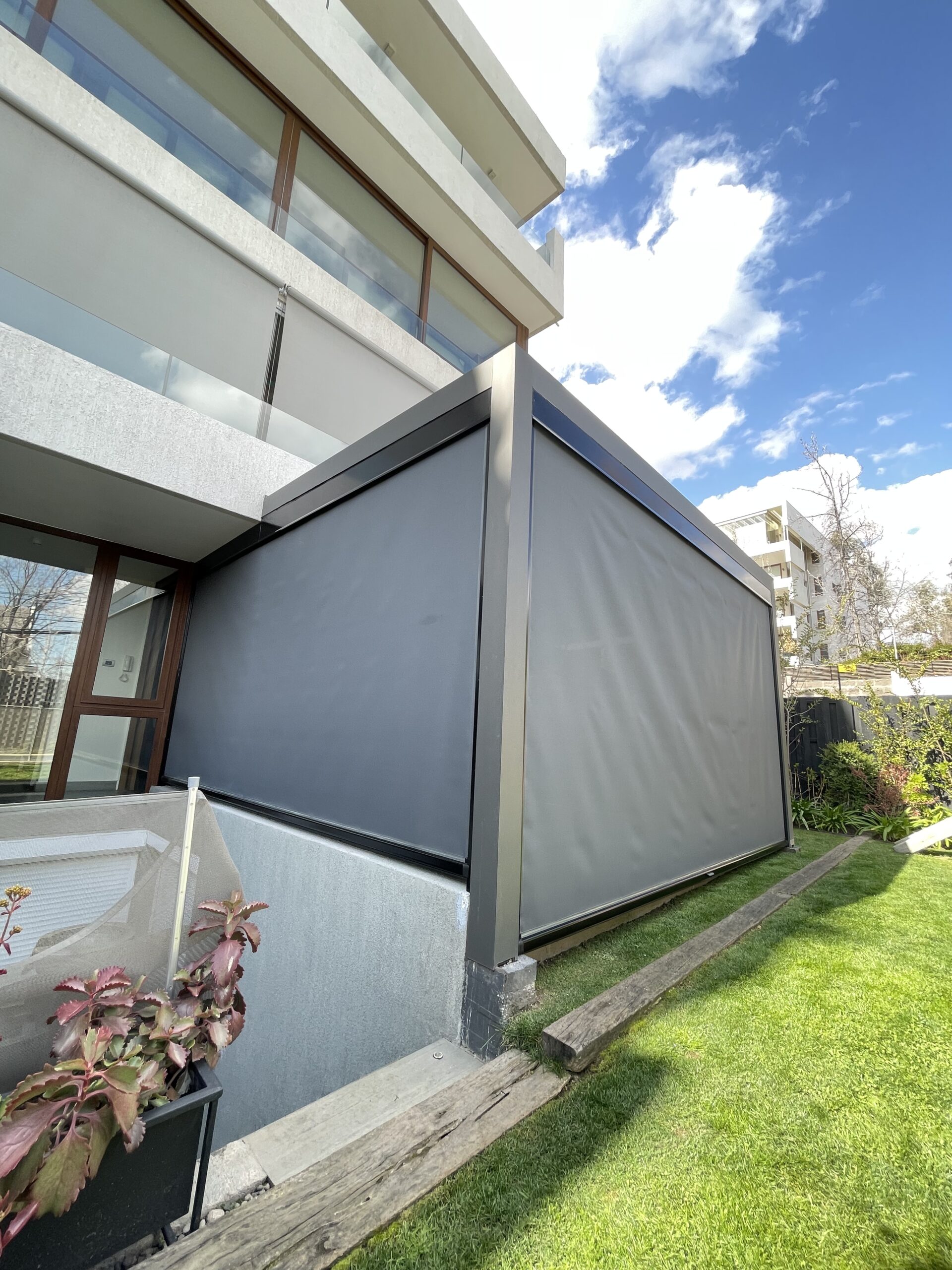 Terraza de departamento moderna con cierre de cristal plegable, amoblada con sofá. Terraza protegida del clima.