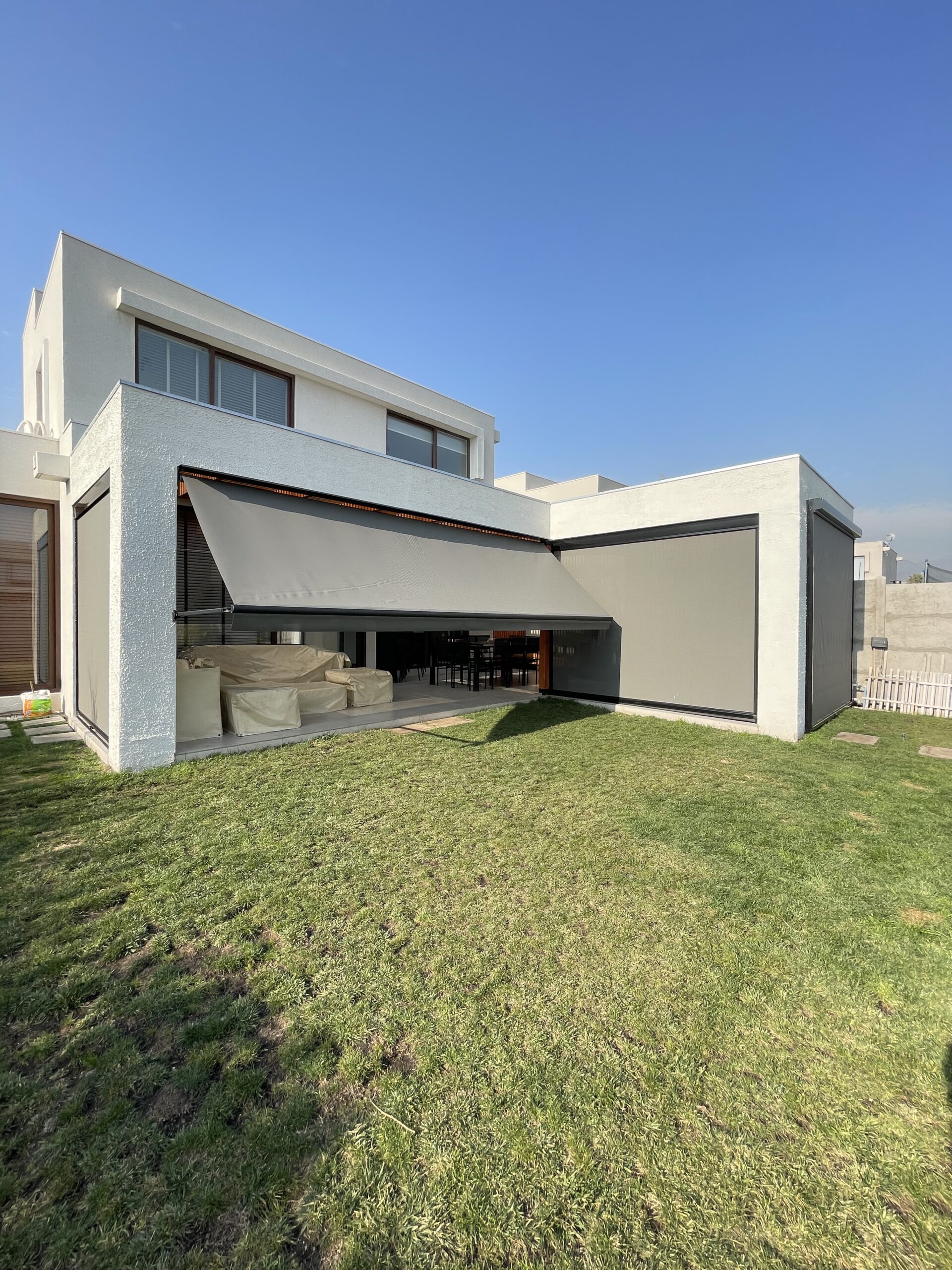 Terraza de departamento moderna con cierre de cristal plegable, amoblada con sofá. Terraza protegida del clima.