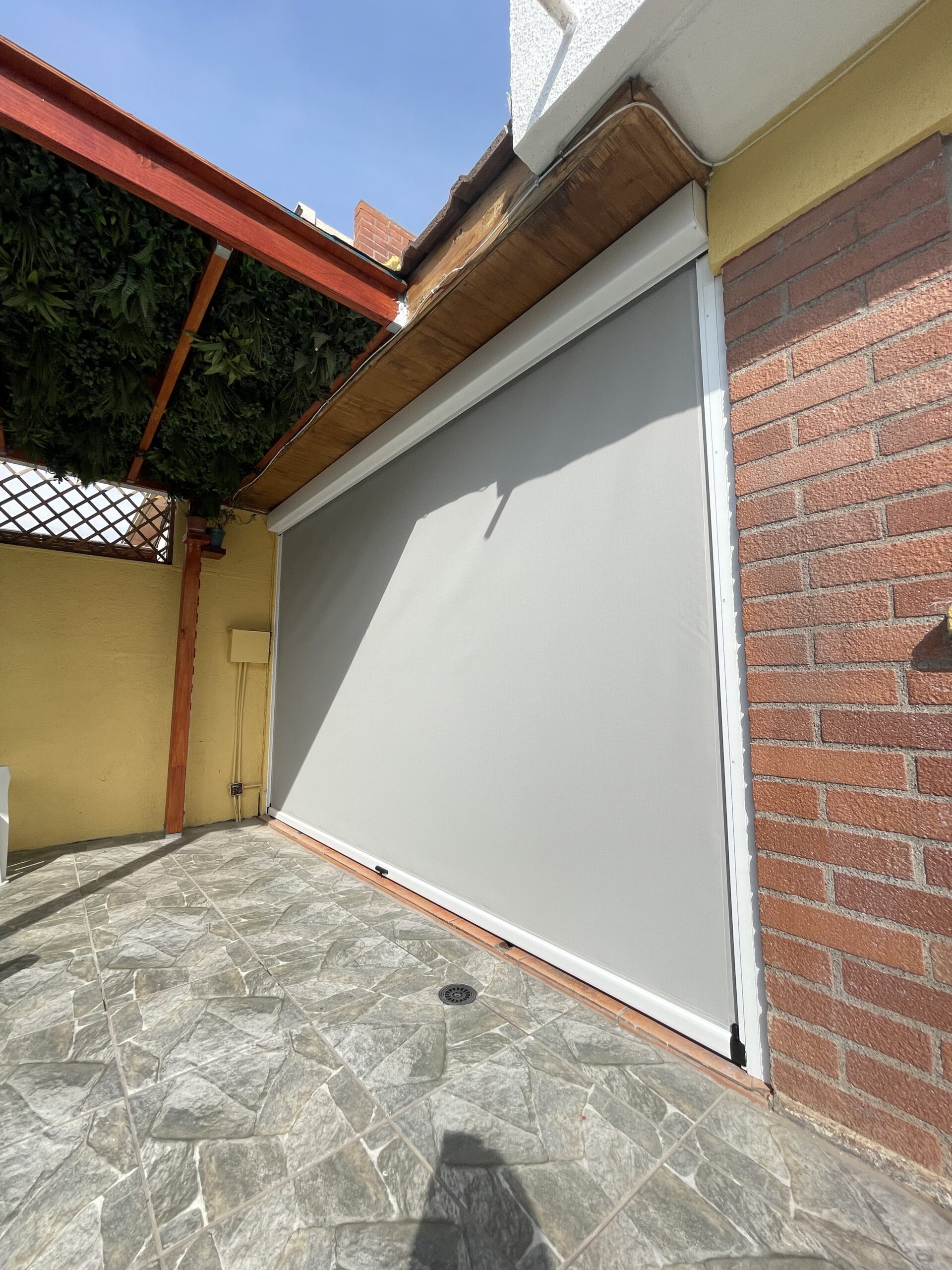 Terraza de departamento moderna con cierre de cristal plegable, amoblada con sofá. Terraza protegida del clima.