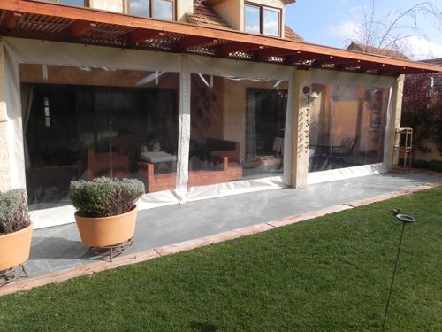 Terraza de departamento moderna con cierre de cristal plegable, amoblada con sofá. Terraza protegida del clima.