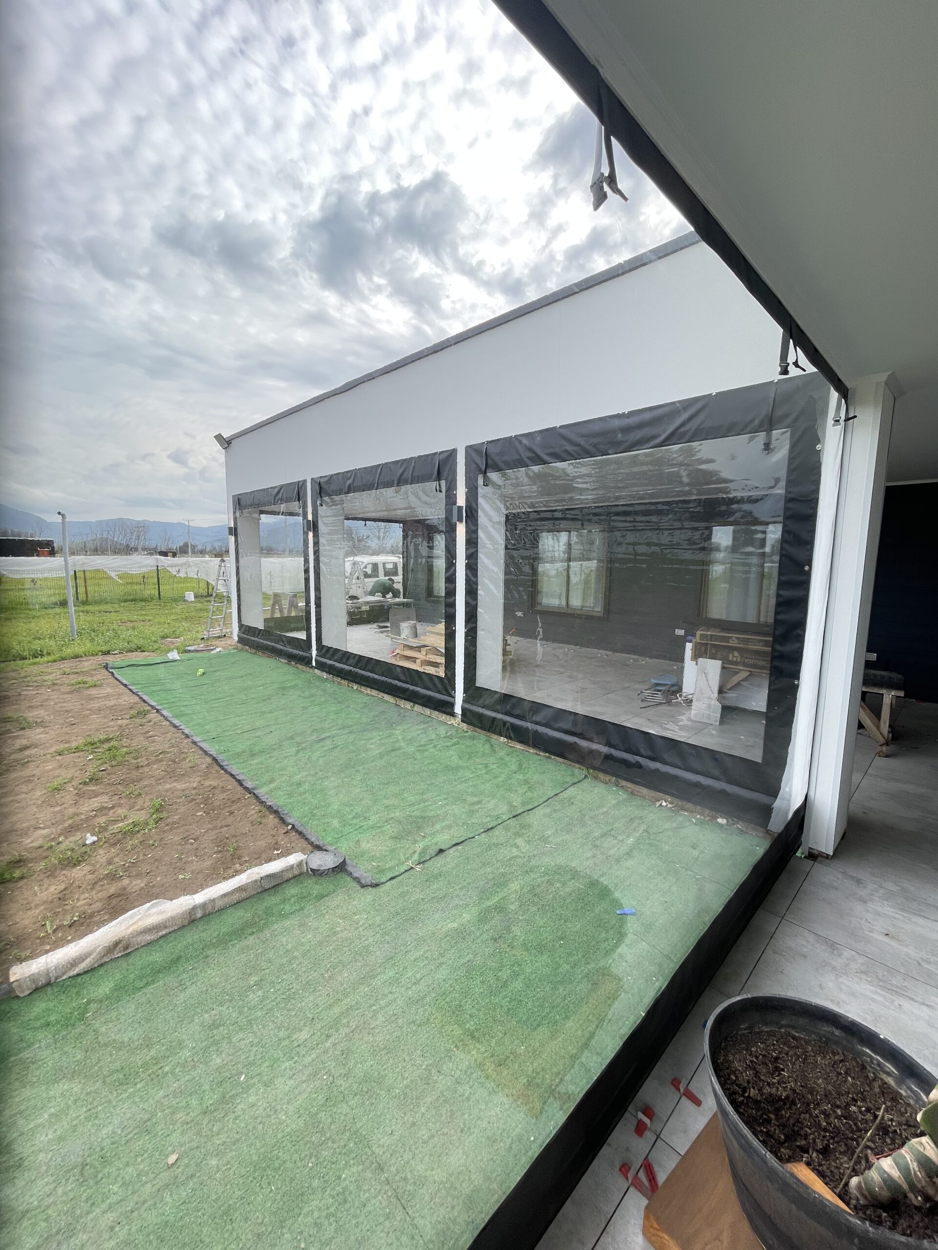 Terraza de departamento moderna con cierre de cristal plegable, amoblada con sofá. Terraza protegida del clima.