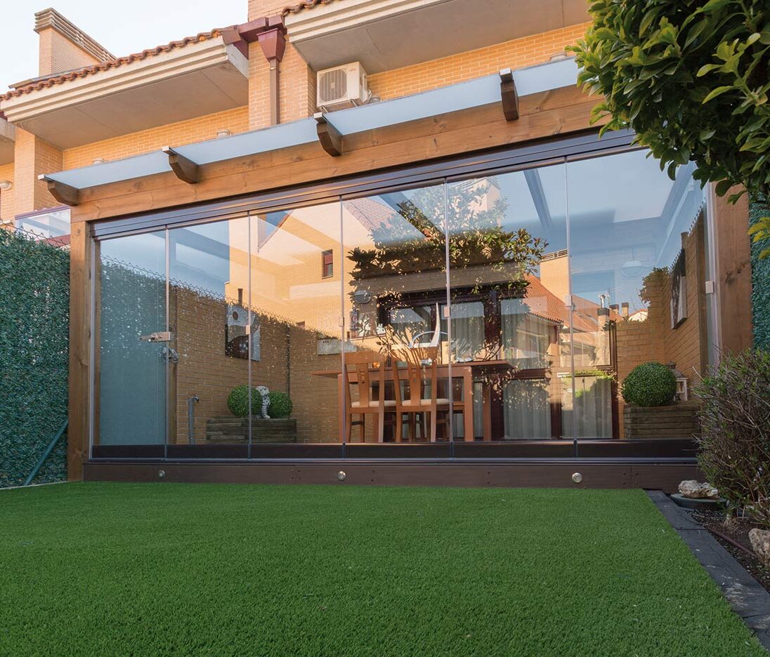Terraza de departamento moderna con cierre de cristal plegable, amoblada con sofá. Terraza protegida del clima.