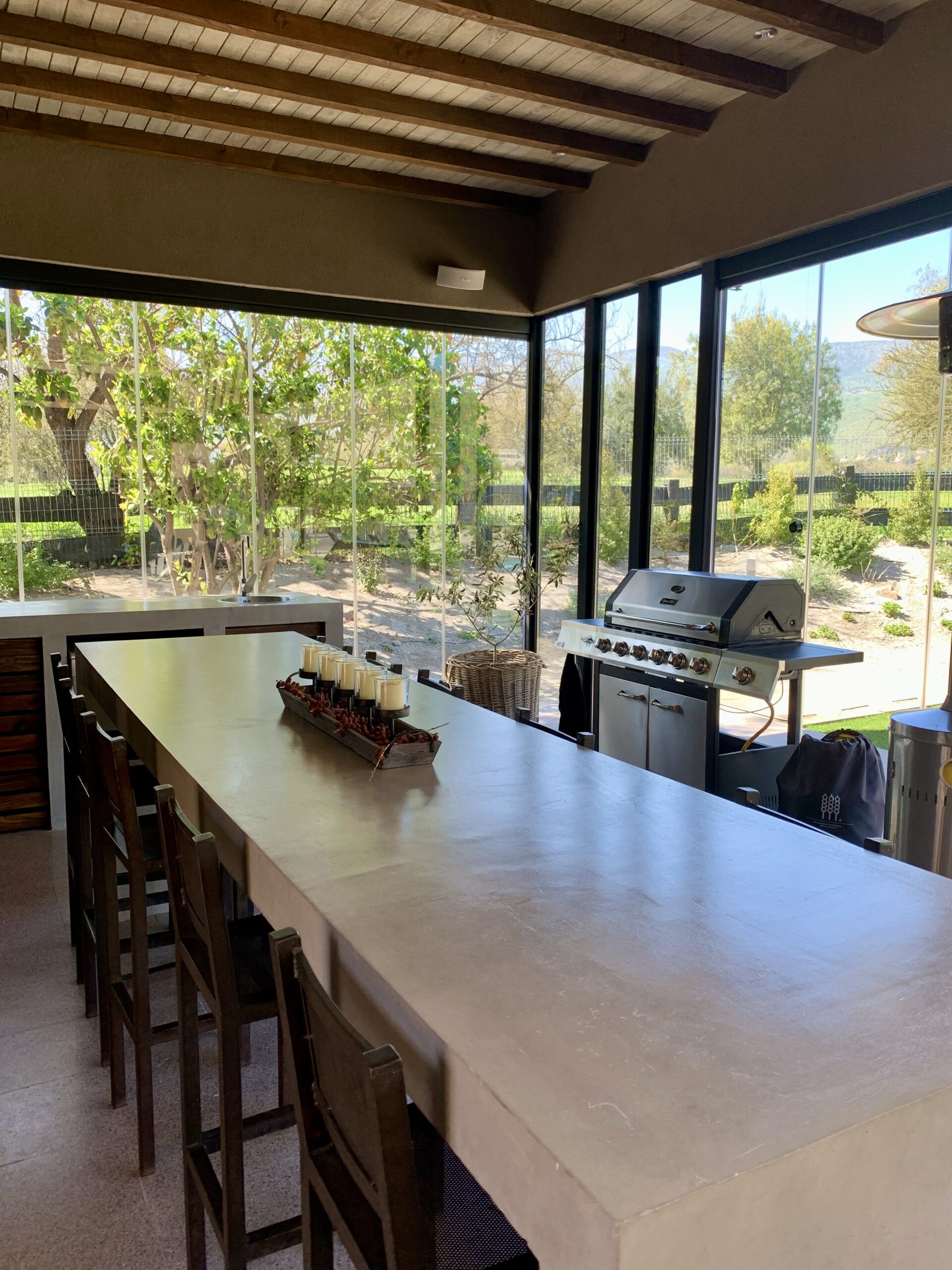 Terraza de departamento moderna con cierre de cristal plegable, amoblada con sofá. Terraza protegida del clima.