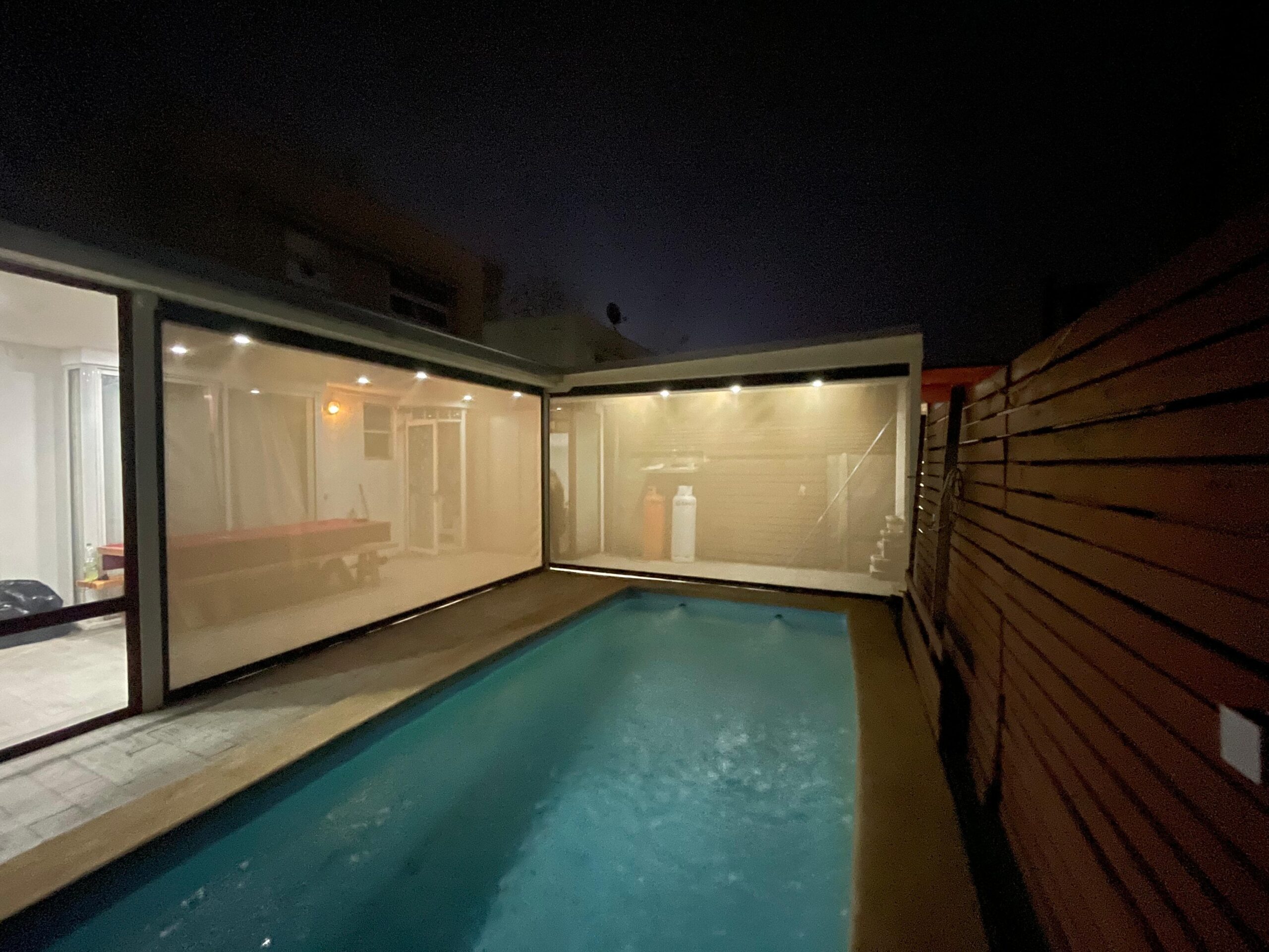 Terraza de departamento moderna con cierre de cristal plegable, amoblada con sofá. Terraza protegida del clima.