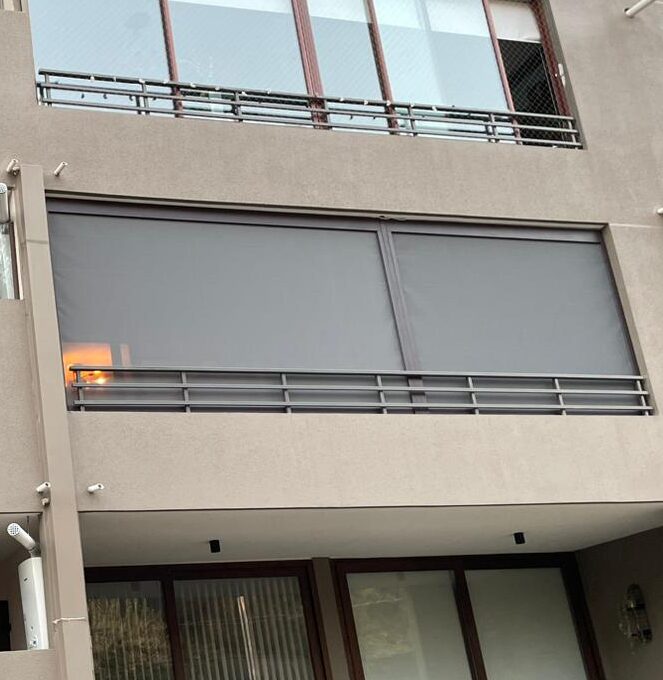 Terraza de departamento moderna con cierre de cristal plegable, amoblada con sofá. Terraza protegida del clima.