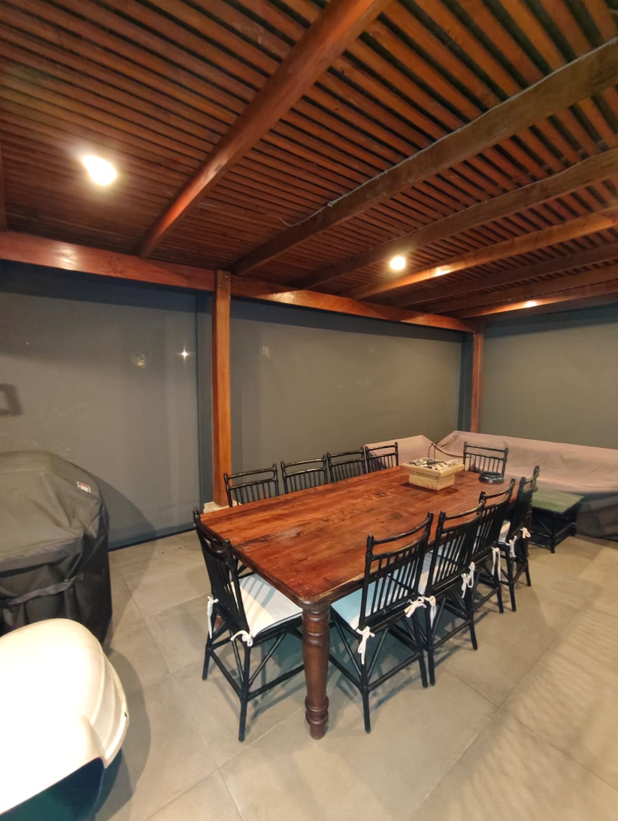 Terraza de departamento moderna con cierre de cristal plegable, amoblada con sofá. Terraza protegida del clima.