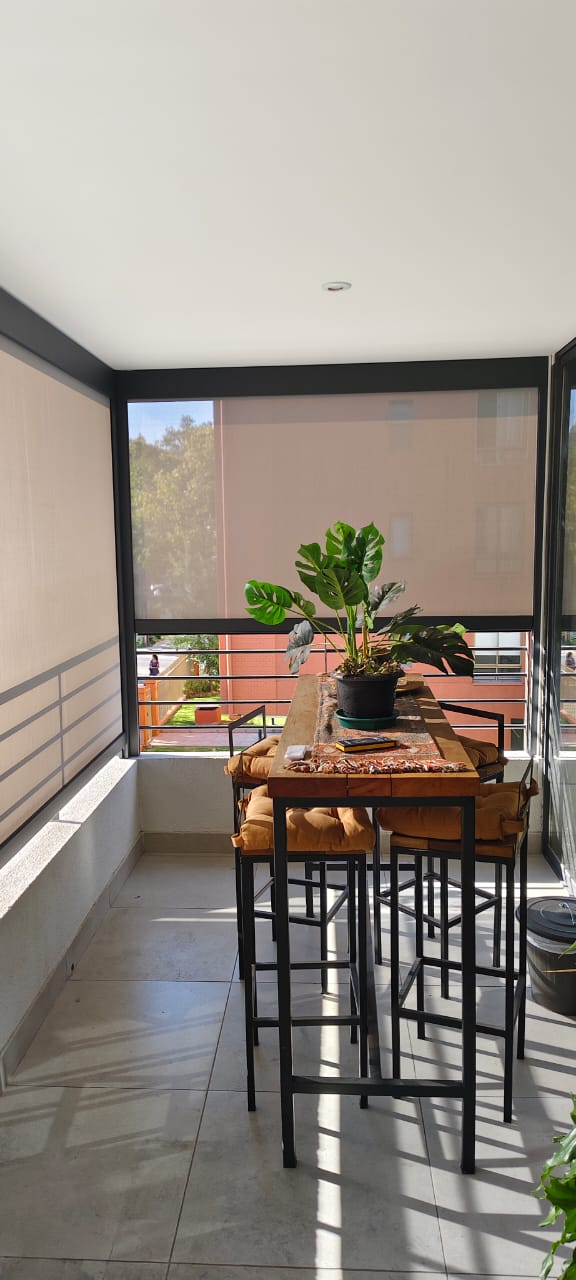 Terraza de departamento moderna con cierre de cristal plegable, amoblada con sofá. Terraza protegida del clima.