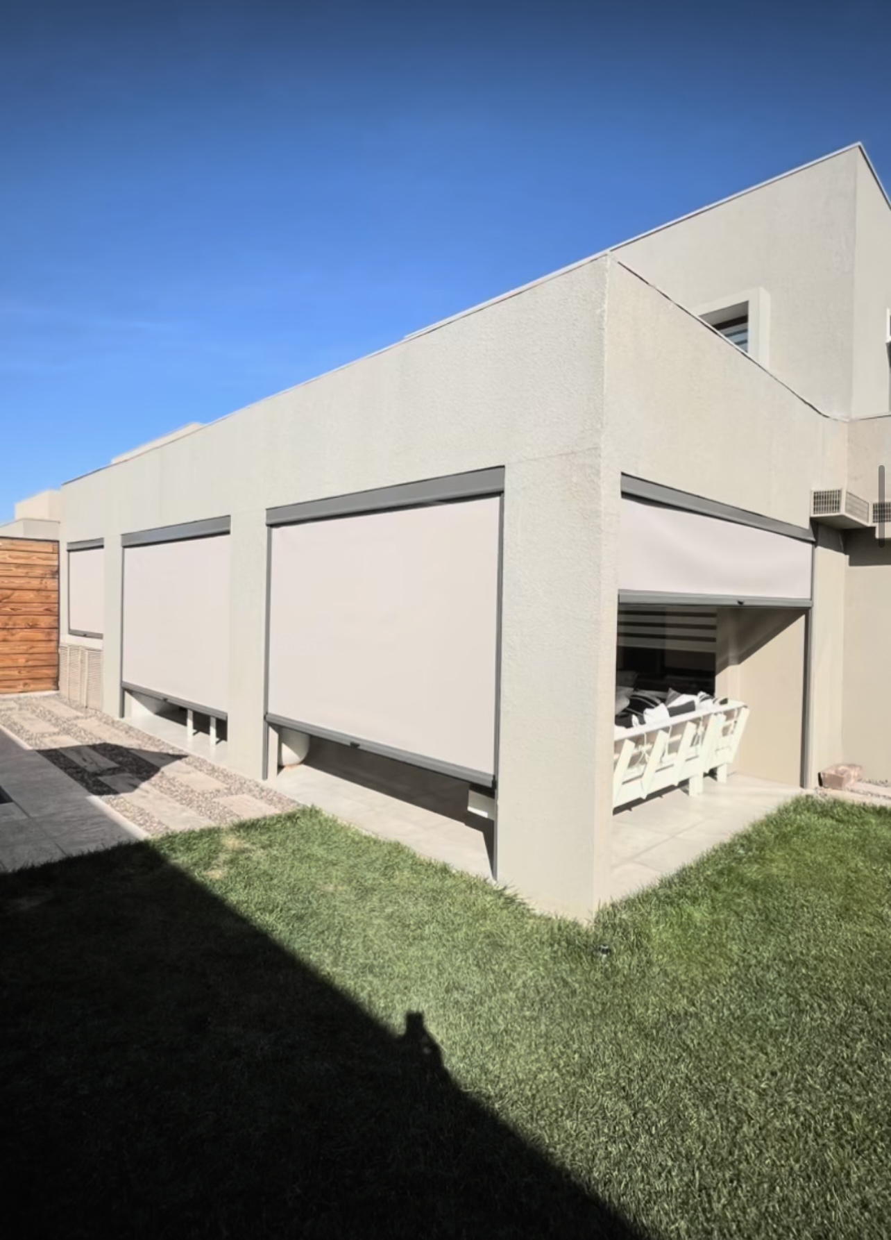 Terraza de departamento moderna con cierre de cristal plegable, amoblada con sofá. Terraza protegida del clima.