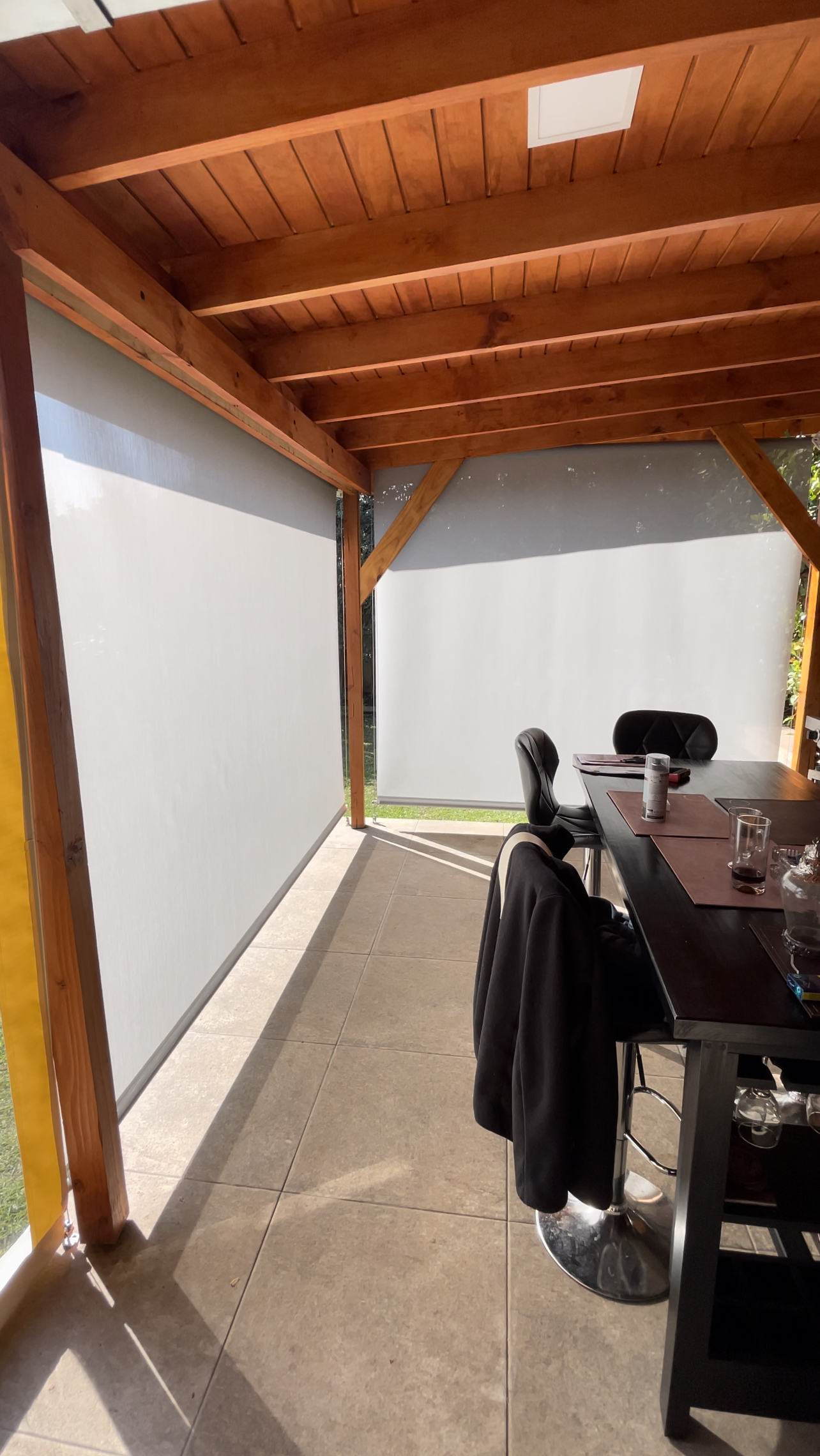 Terraza de departamento moderna con cierre de cristal plegable, amoblada con sofá. Terraza protegida del clima.