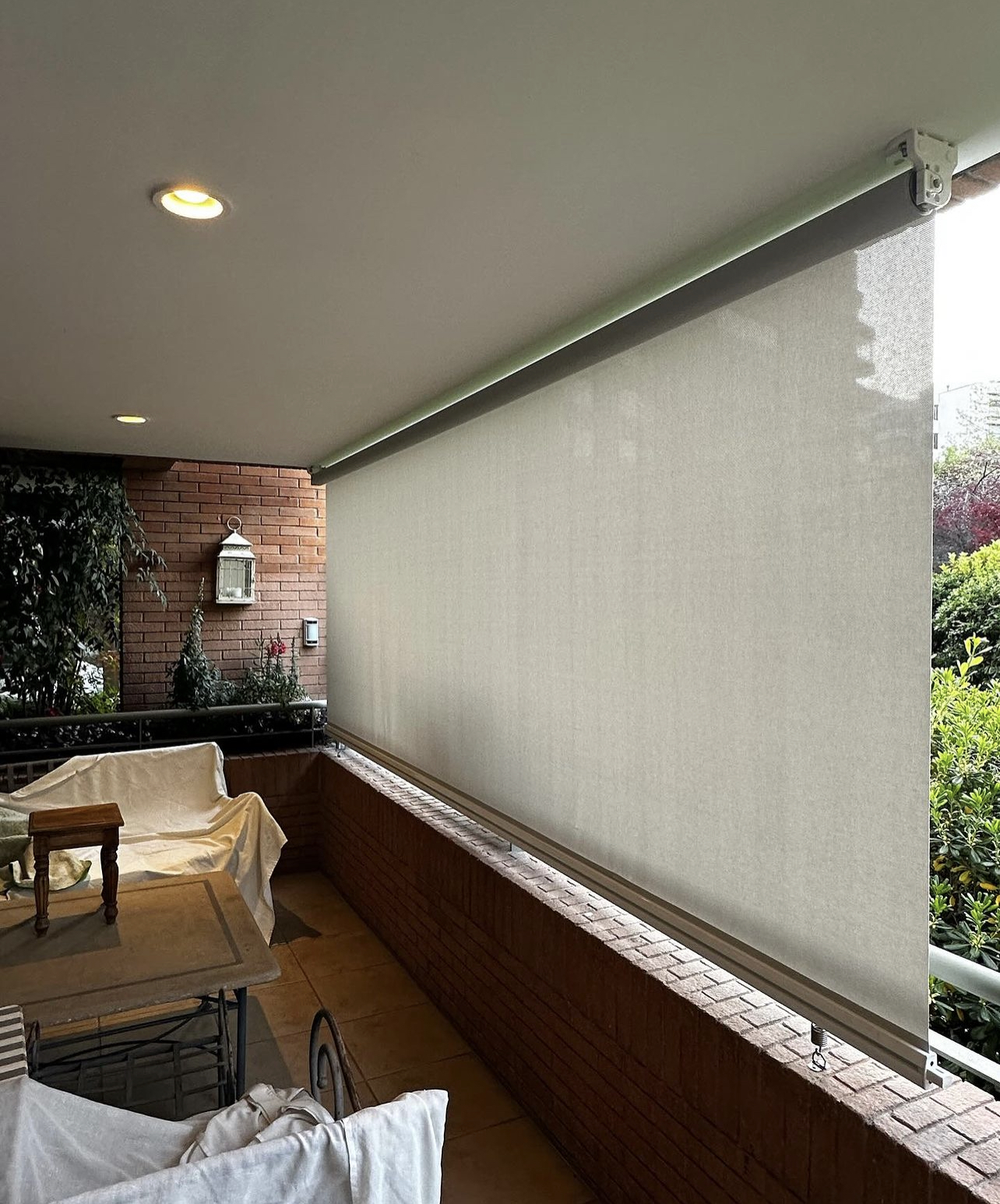 Terraza de departamento moderna con cierre de cristal plegable, amoblada con sofá. Terraza protegida del clima.