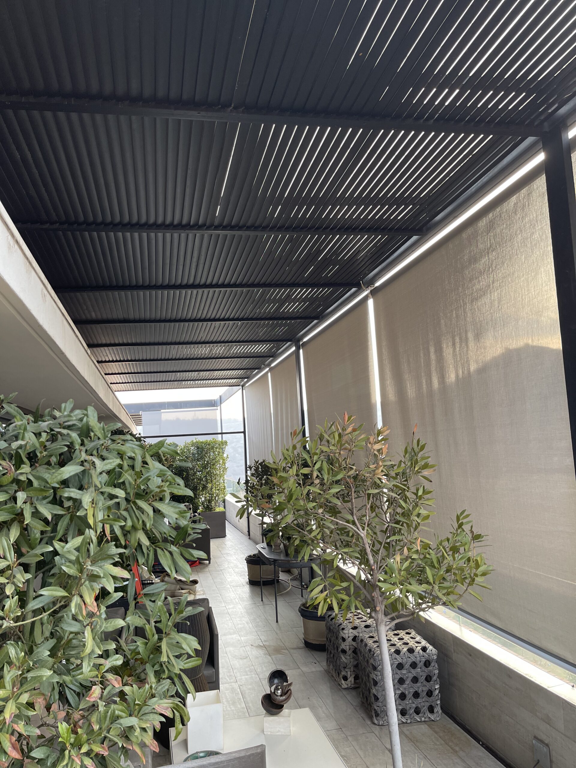 Terraza de departamento moderna con cierre de cristal plegable, amoblada con sofá. Terraza protegida del clima.