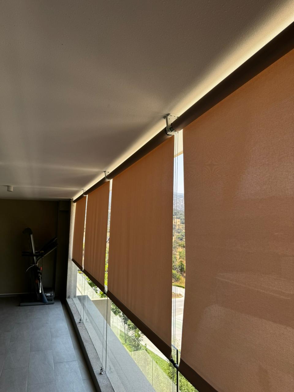 Terraza de departamento moderna con cierre de cristal plegable, amoblada con sofá. Terraza protegida del clima.