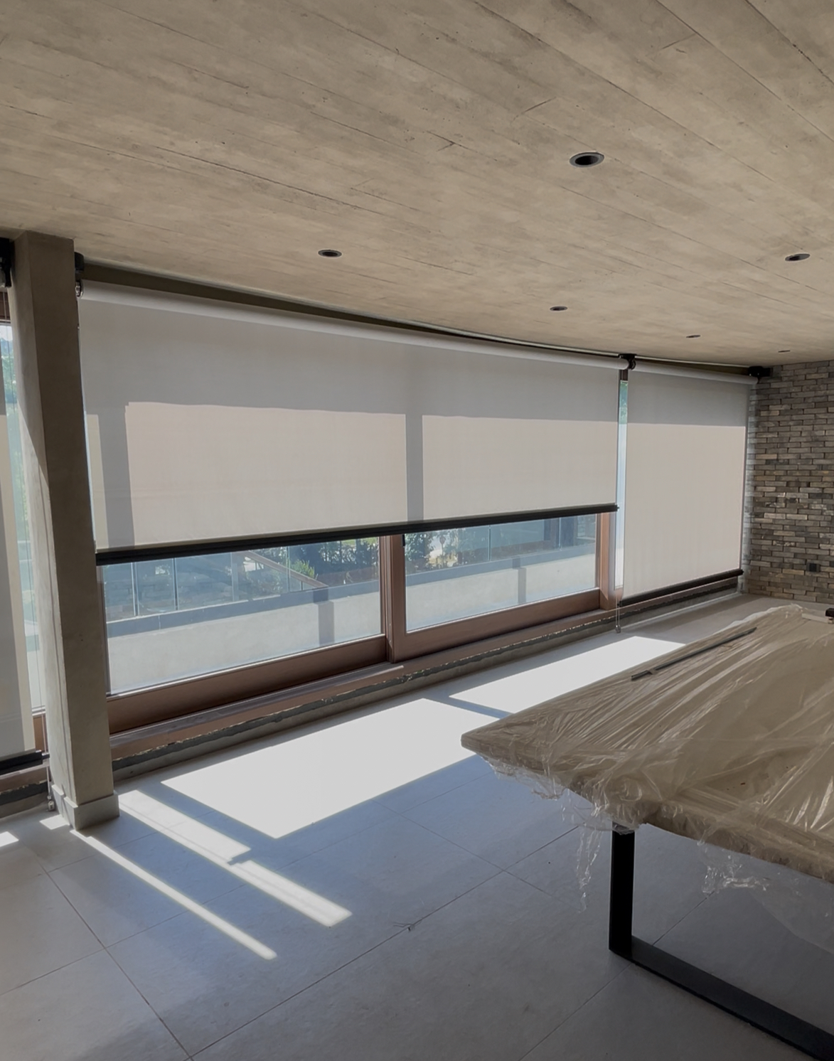 Terraza de departamento moderna con cierre de cristal plegable, amoblada con sofá. Terraza protegida del clima.