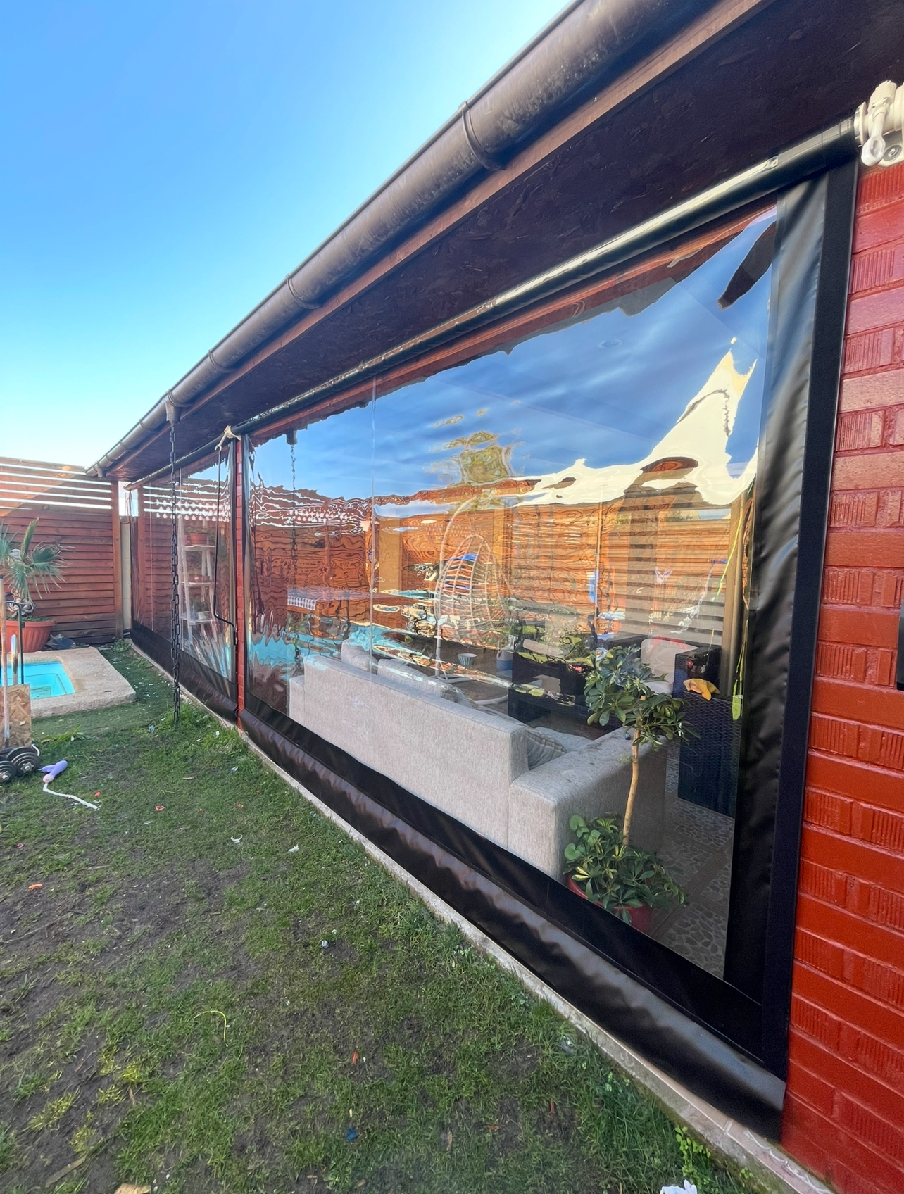 Terraza de departamento moderna con cierre de cristal plegable, amoblada con sofá. Terraza protegida del clima.