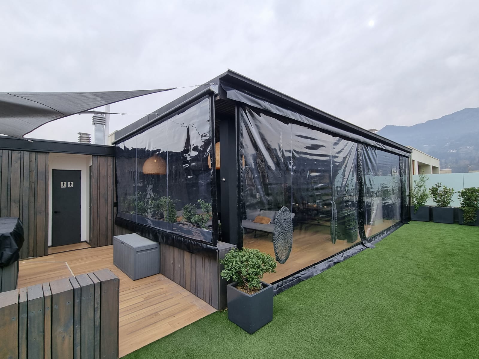 Terraza de departamento moderna con cierre de cristal plegable, amoblada con sofá. Terraza protegida del clima.