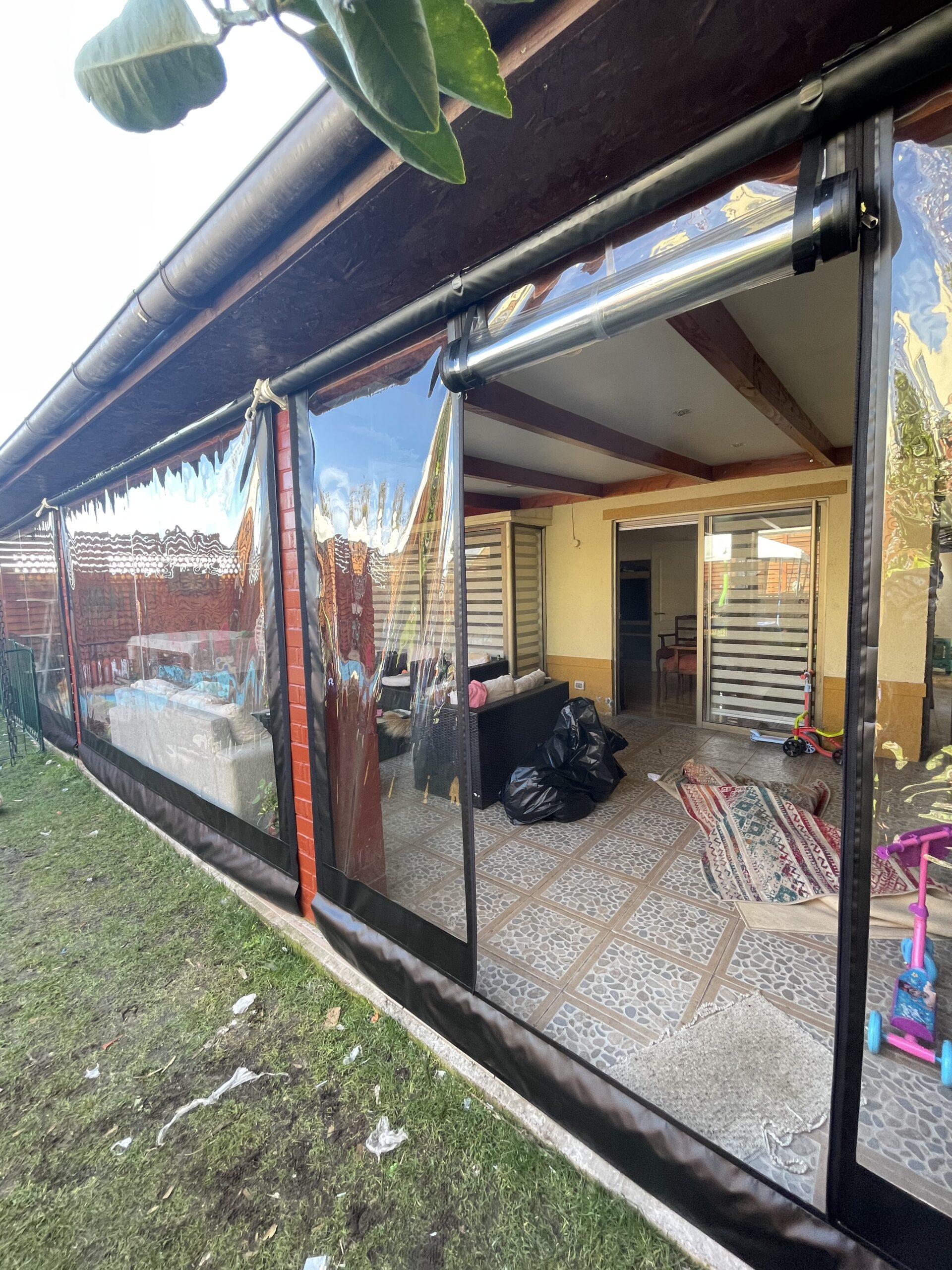 Terraza de departamento moderna con cierre de cristal plegable, amoblada con sofá. Terraza protegida del clima.