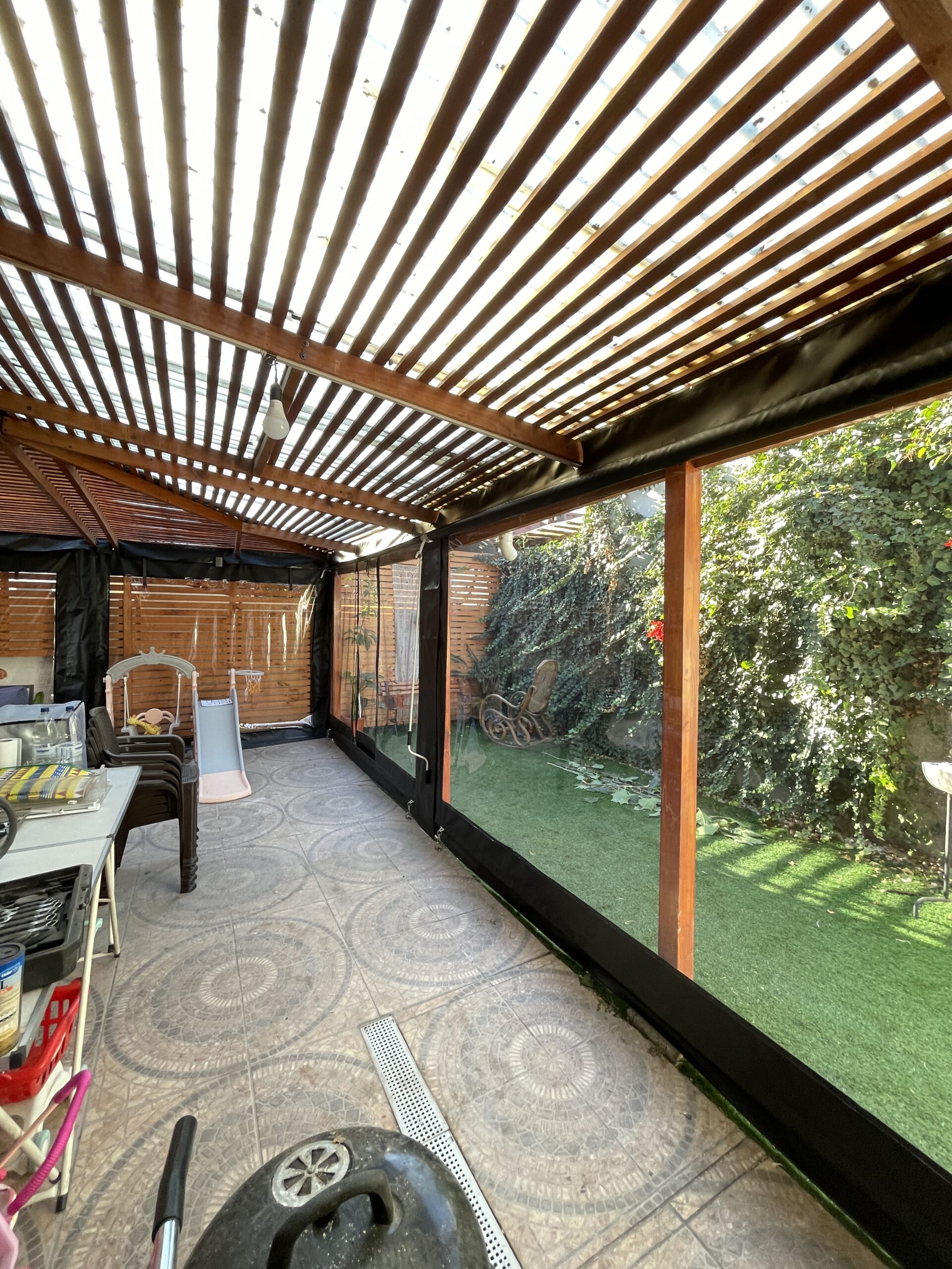 Terraza de departamento moderna con cierre de cristal plegable, amoblada con sofá. Terraza protegida del clima.