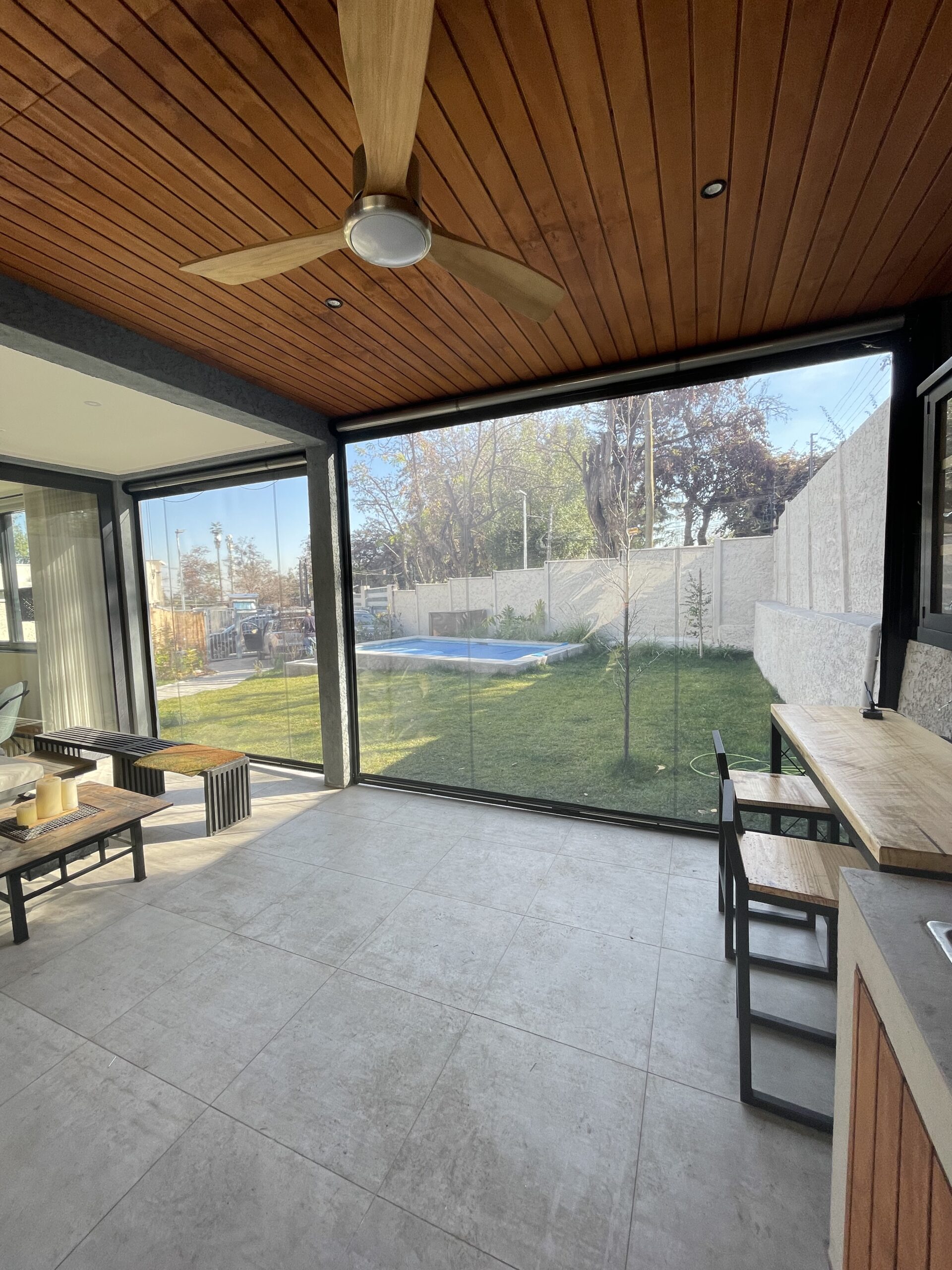 Terraza de departamento moderna con cierre de cristal plegable, amoblada con sofá. Terraza protegida del clima.