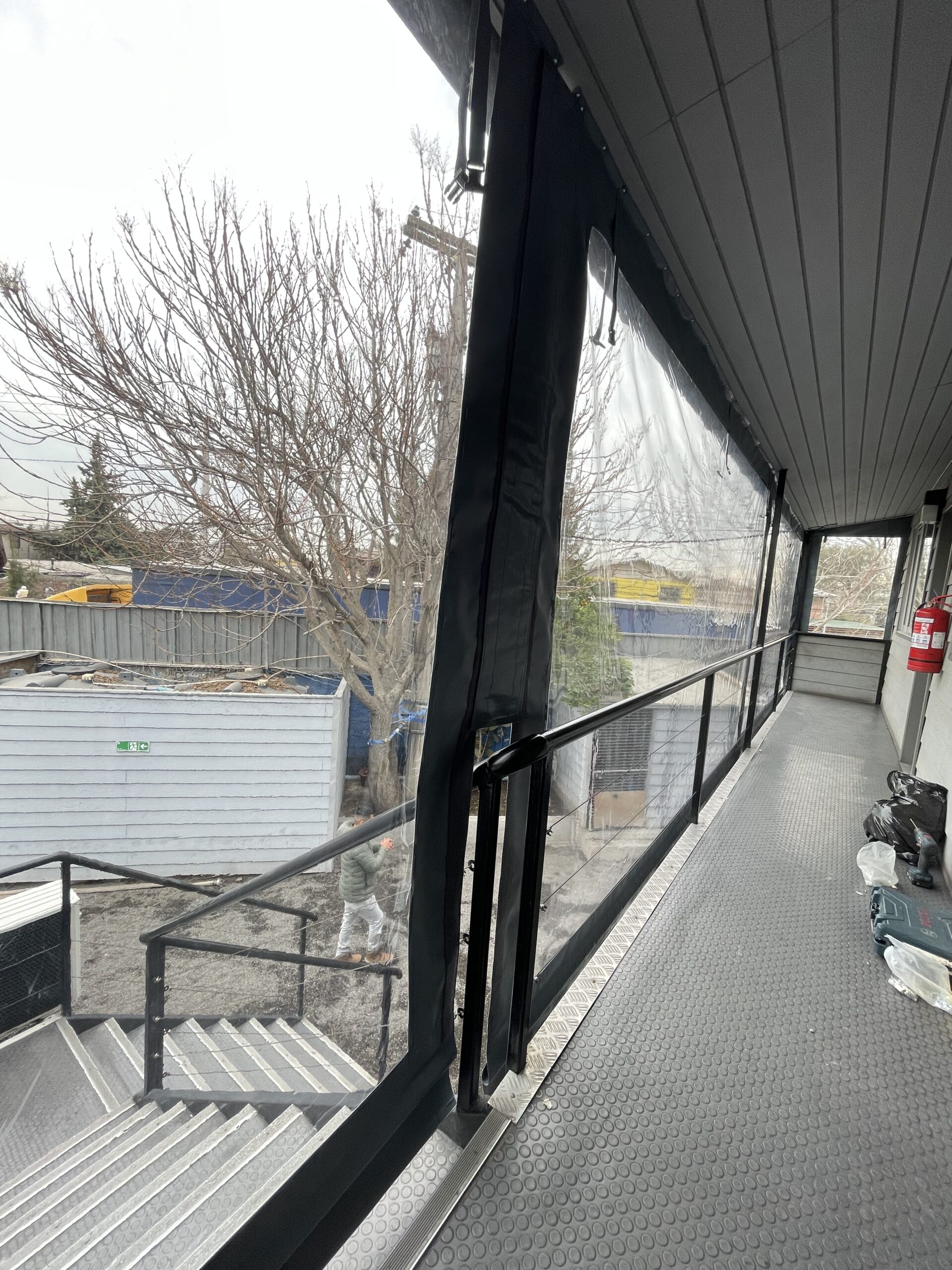 Terraza de departamento moderna con cierre de cristal plegable, amoblada con sofá. Terraza protegida del clima.