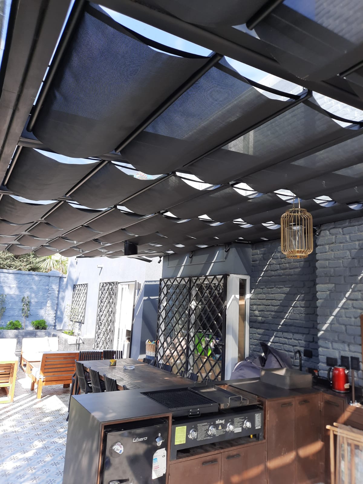 Terraza de departamento moderna con cierre de cristal plegable, amoblada con sofá. Terraza protegida del clima.